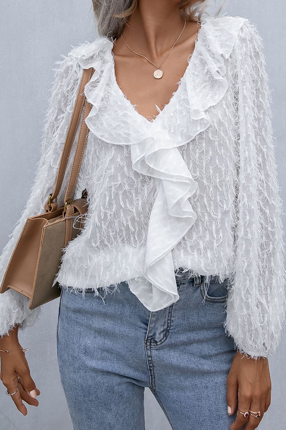 White ruffle-front balloon sleeve blouse with textured fabric and fringe hem