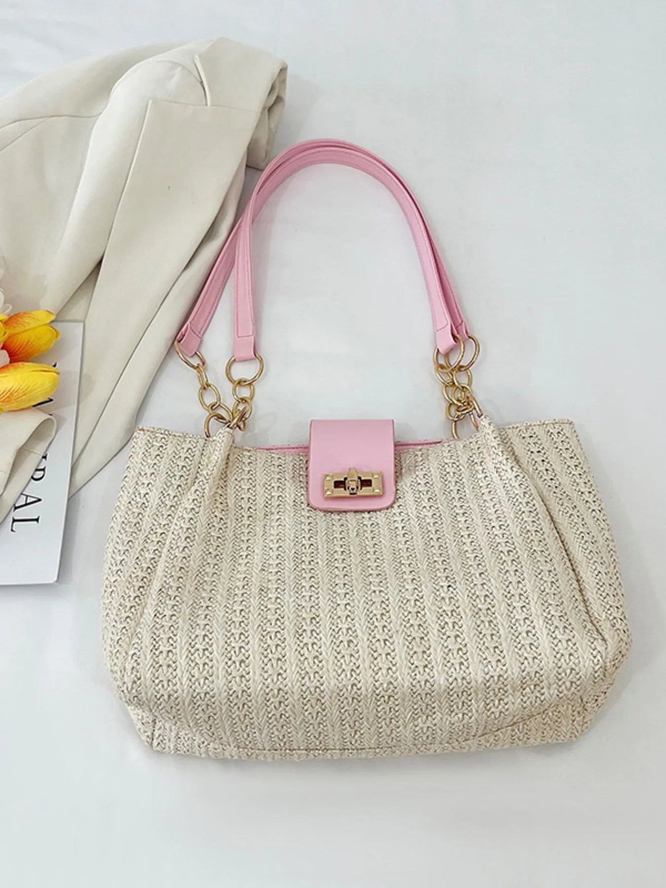 Woven straw shoulder bag with pink handles and gold-tone chain, beige woven bag