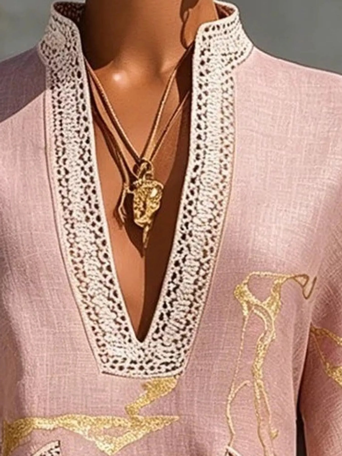 Pink mini dress neckline close-up with notched V lace trim and gold horse motif