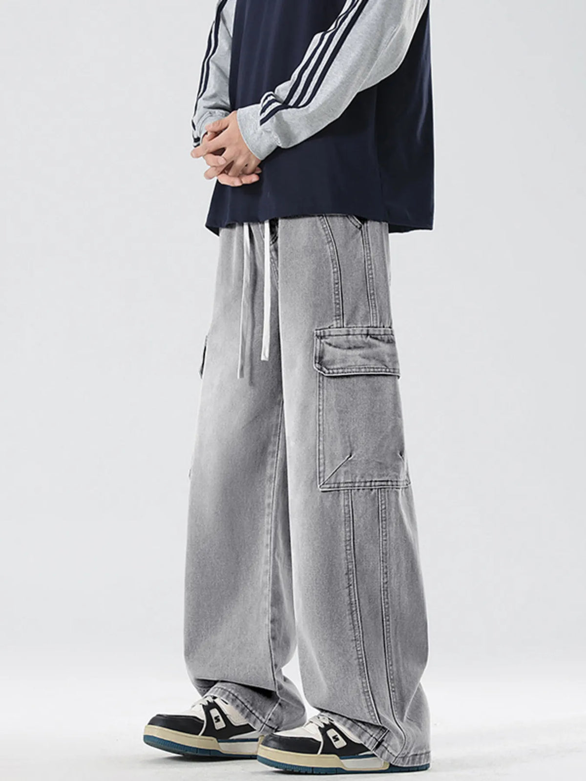Washed light gray wide-leg cargo jeans showing knee patch pocket and hanging drawcords