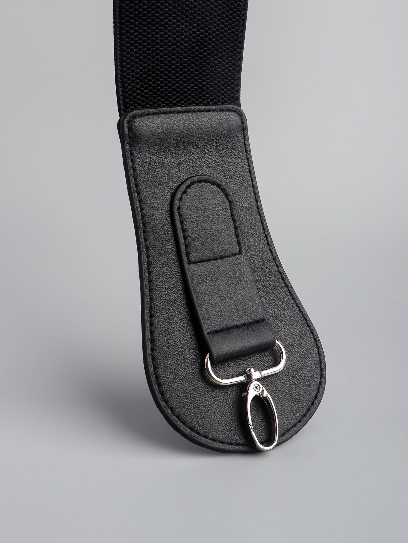 Black wide elastic belt close-up with stitched leather end and silver buckle hardware