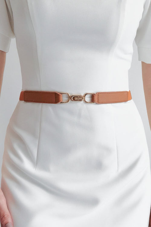 Caramel elastic buckle belt worn over a white dress, silver-tone hardware