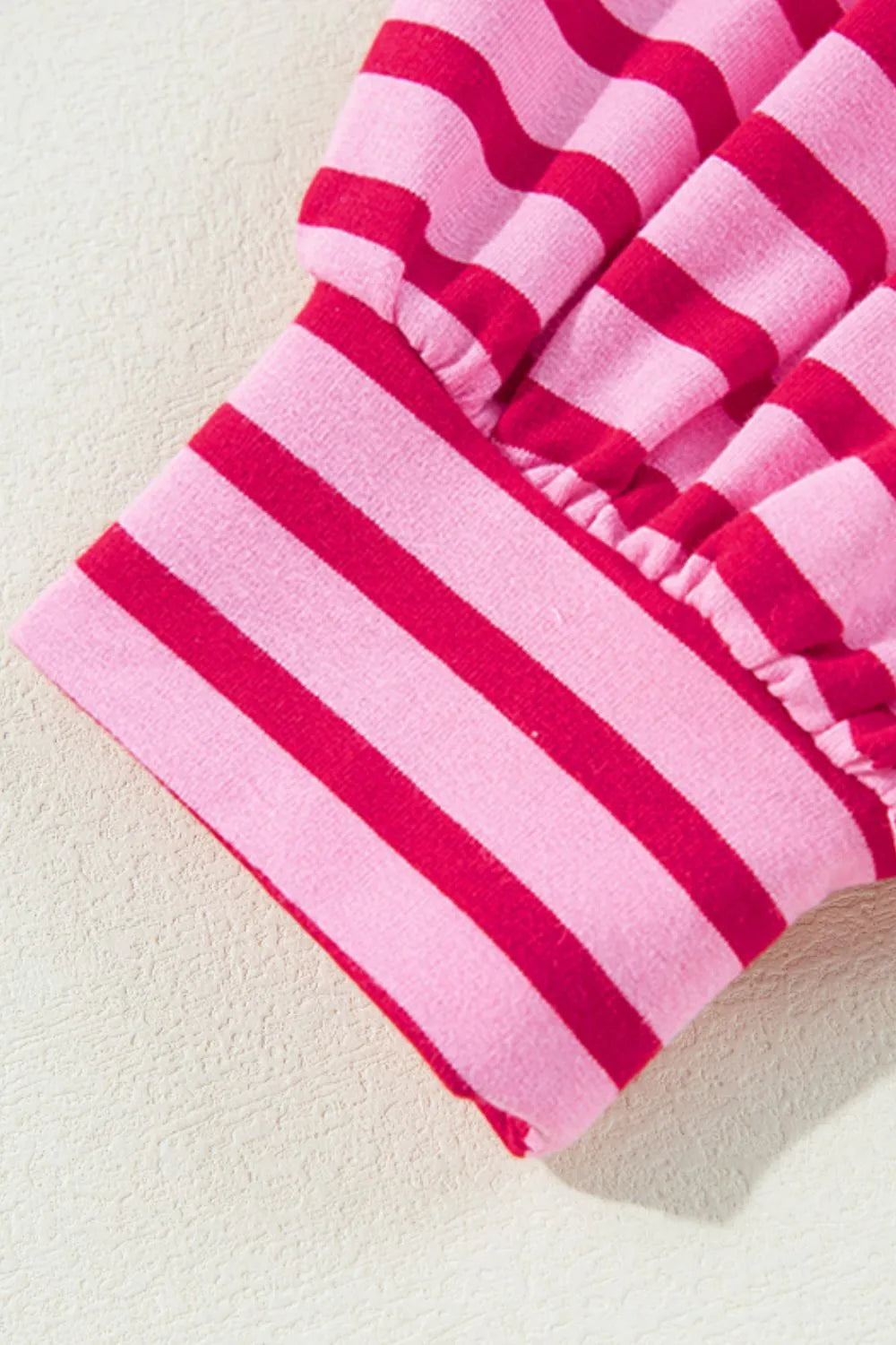 Hot pink and white striped sweatshirt sleeve cuff with elastic hem.