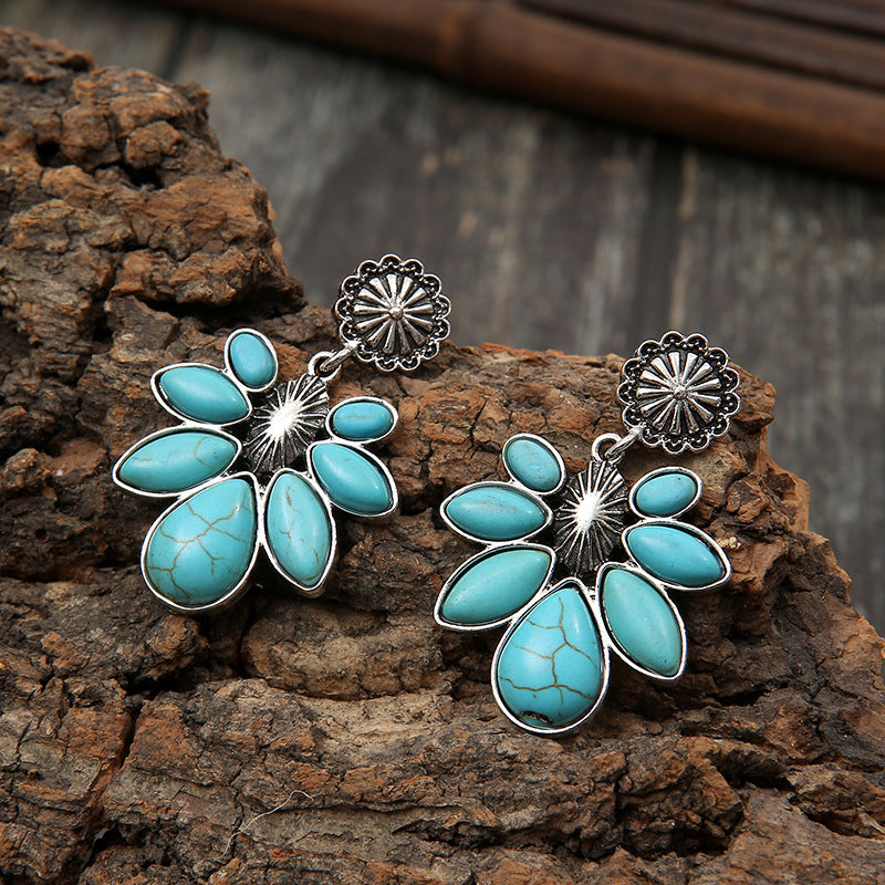 Turquoise flower drop earrings with turquoise oval petals and silver-tone filigree discs.