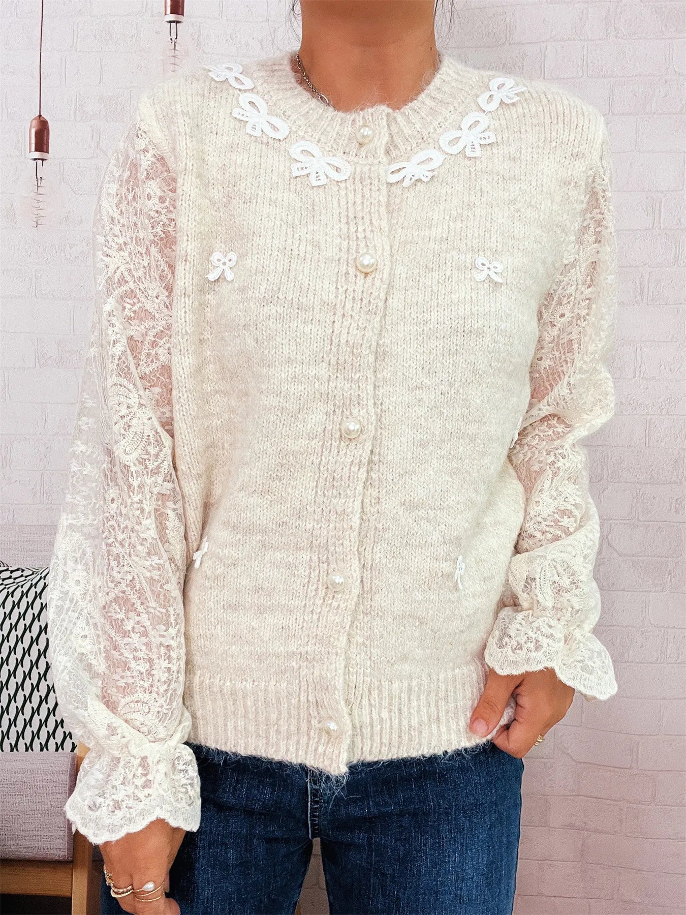 Cream lace-sleeve button-up cardigan with embroidered bow accents and button placket