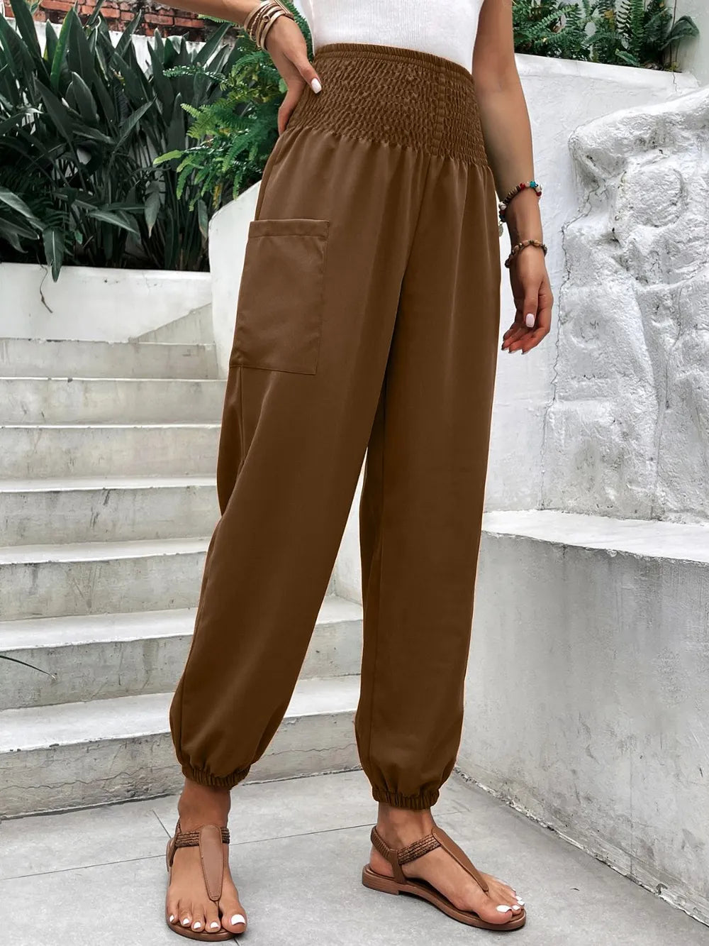 Brown smocked high-rise jogger pants with side pockets and tapered ankle cuffs