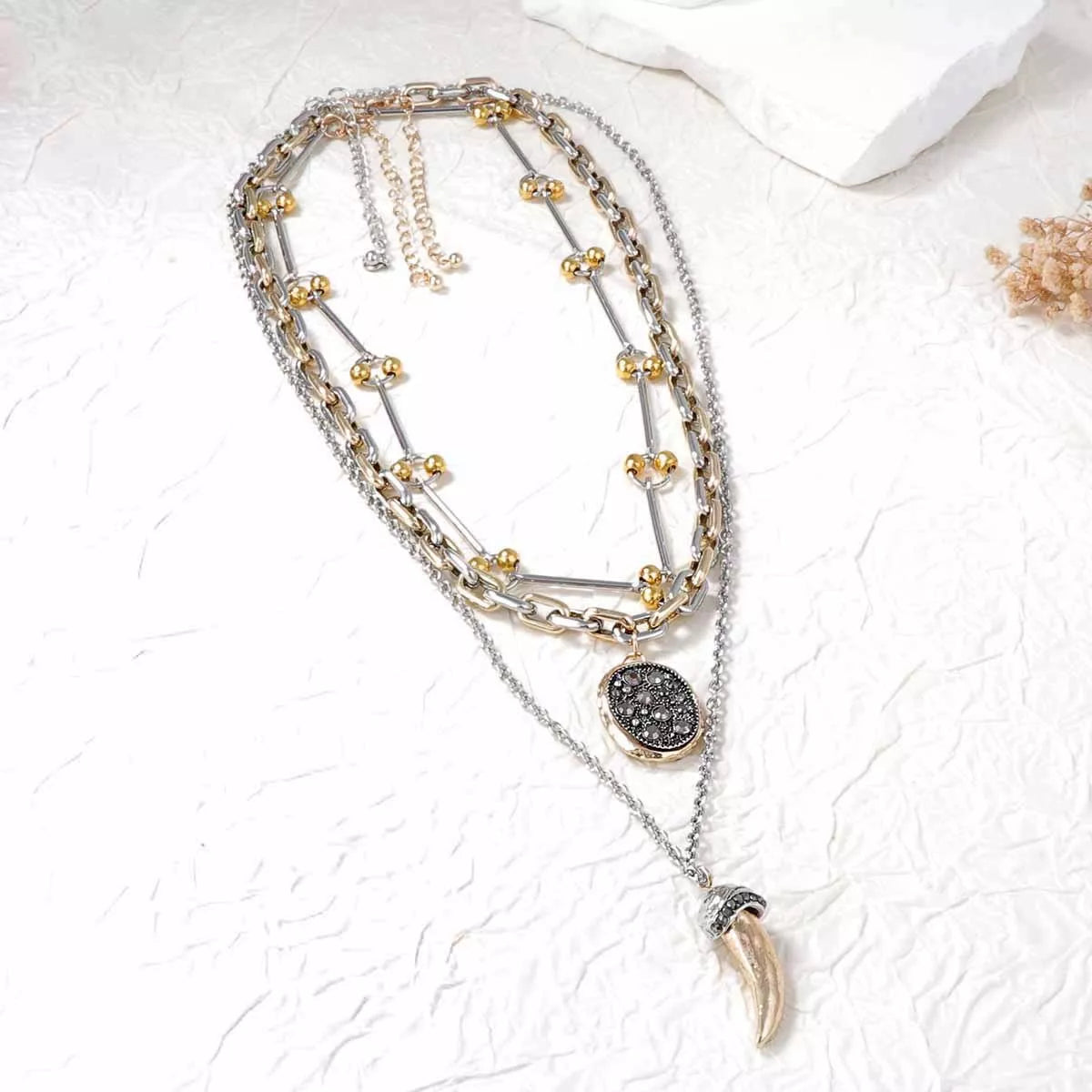 Layered gold plated chain necklace featuring dark round disc and horn pendant