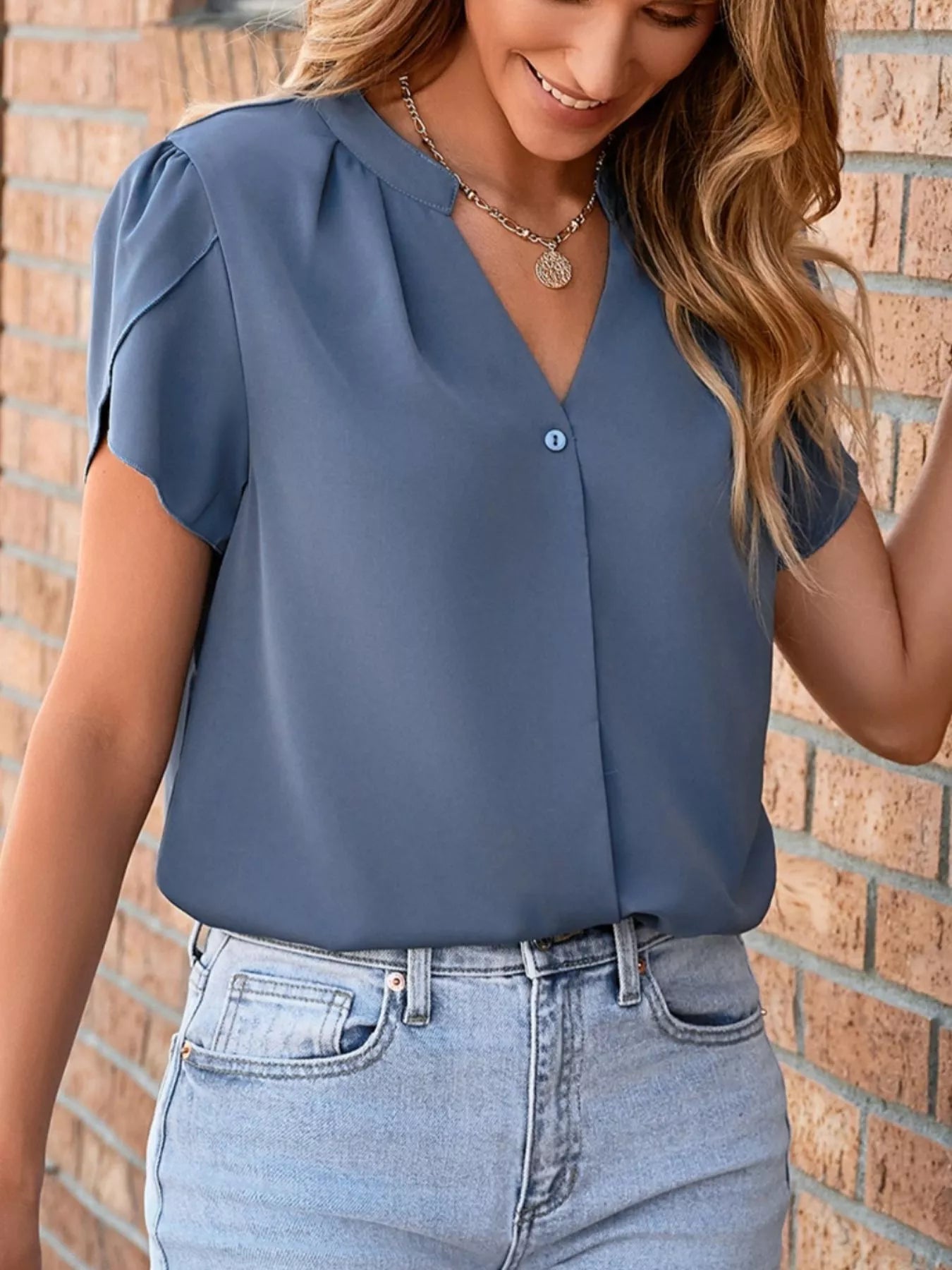 Notched Petal Sleeve Blouse in blue with a single front button and V-neck, paired with light denim jeans