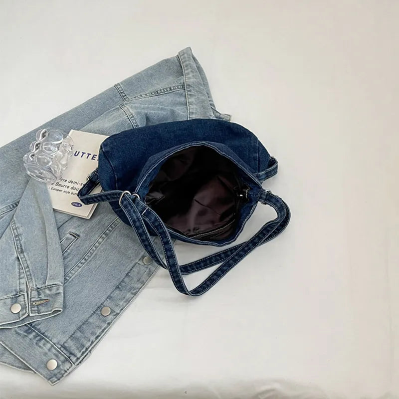 Blue denim shoulder bag open at top, showing dark interior and adjustable strap