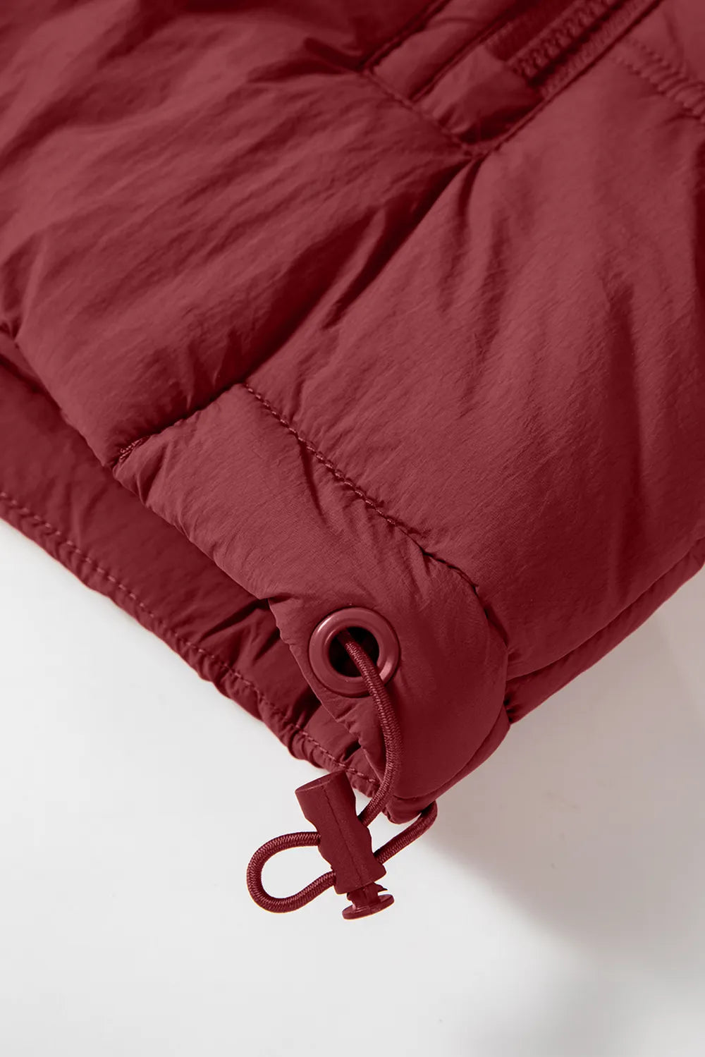 Burgundy hooded vest coat cuff close-up with drawstring ring and zipper