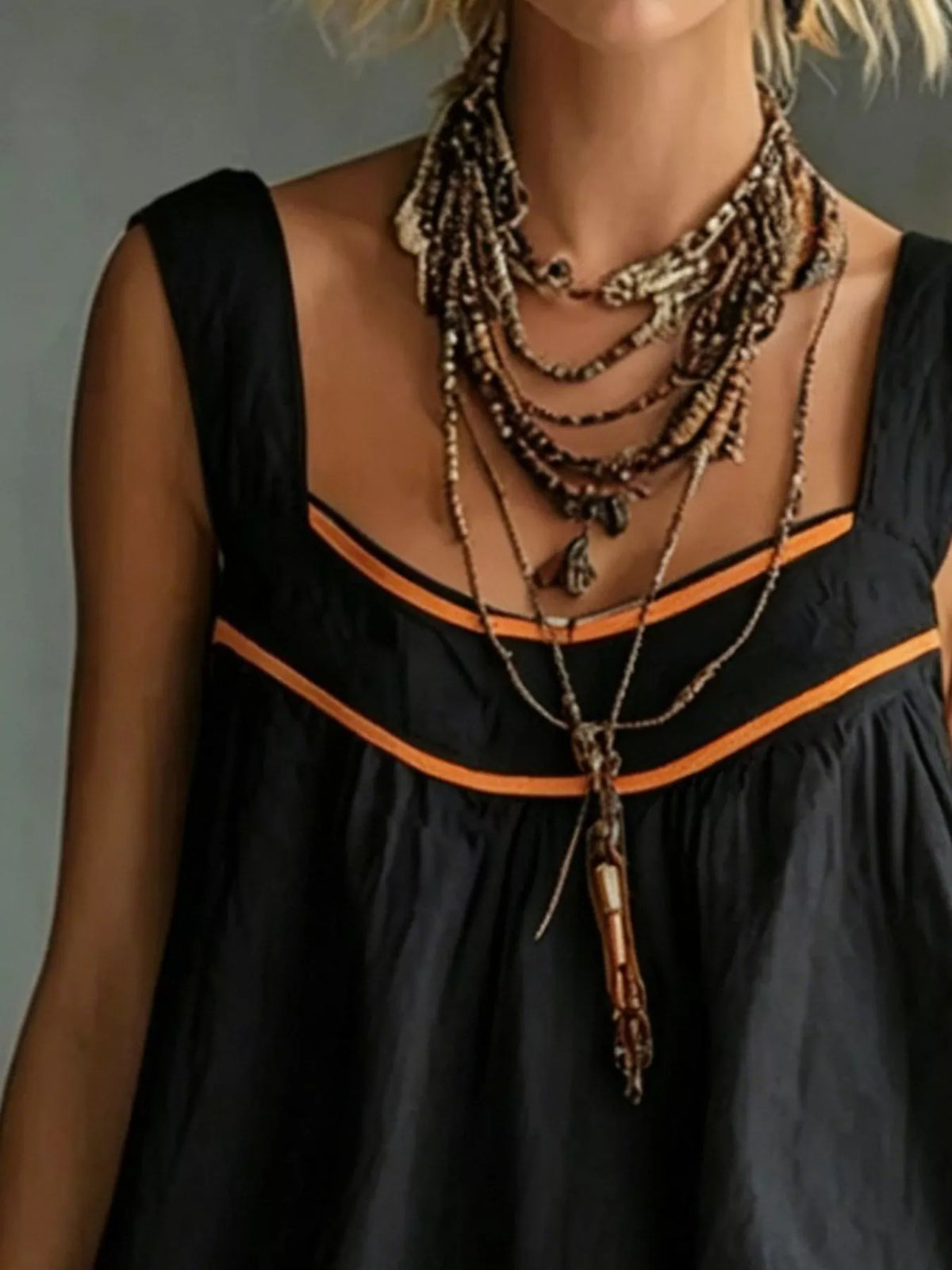 Black sleeveless mini dress with orange trim, V neckline, and tiered ruffle skirt
