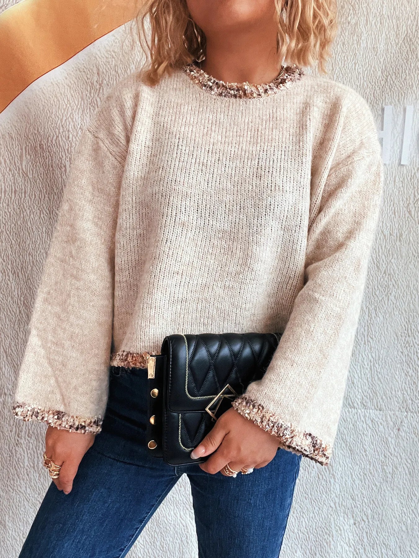 Light gray cropped round-neck sweater with sparkly trim around neckline and cuffs