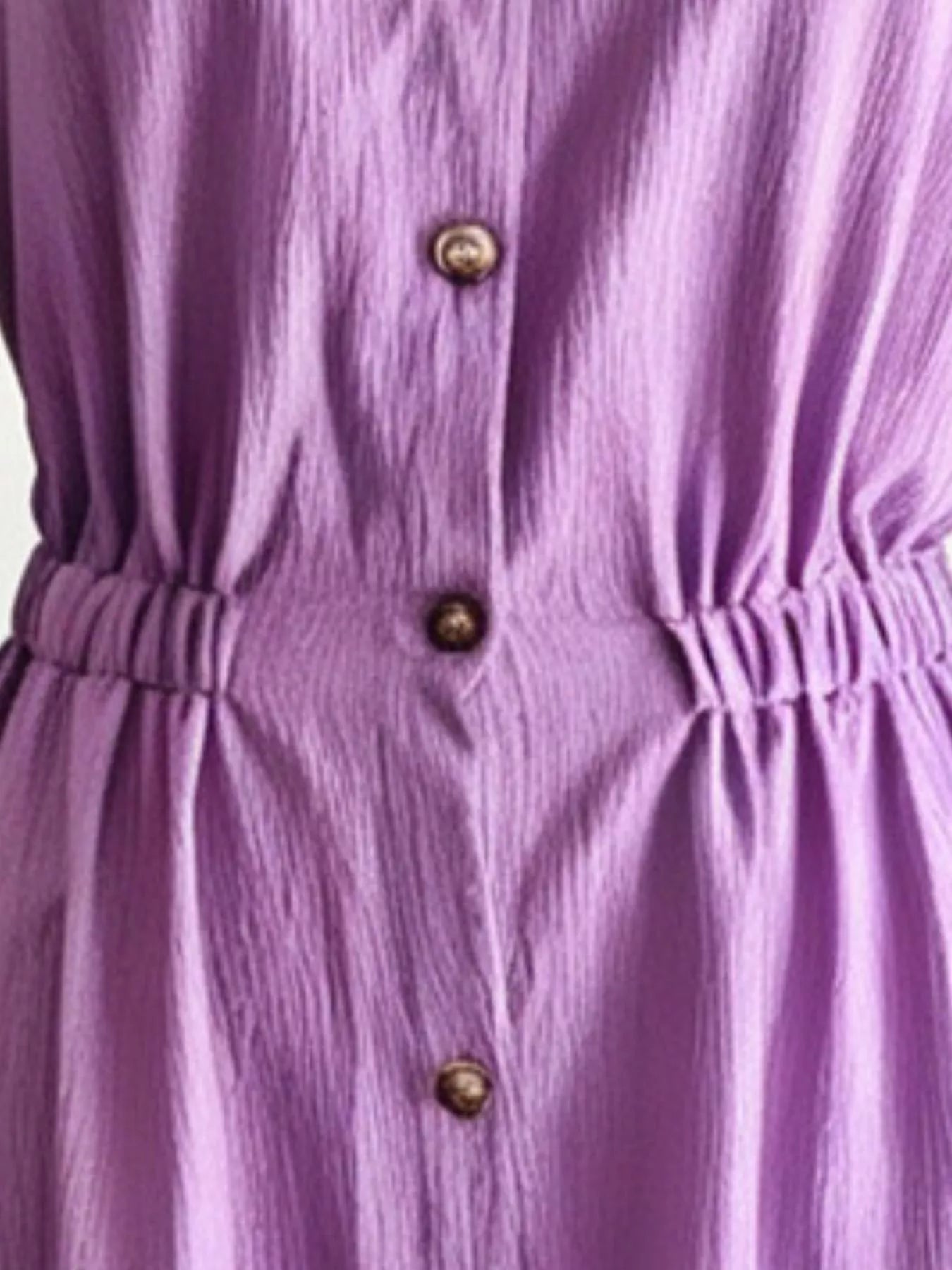 Close-up of purple button-front long dress with gathered waist and gold buttons