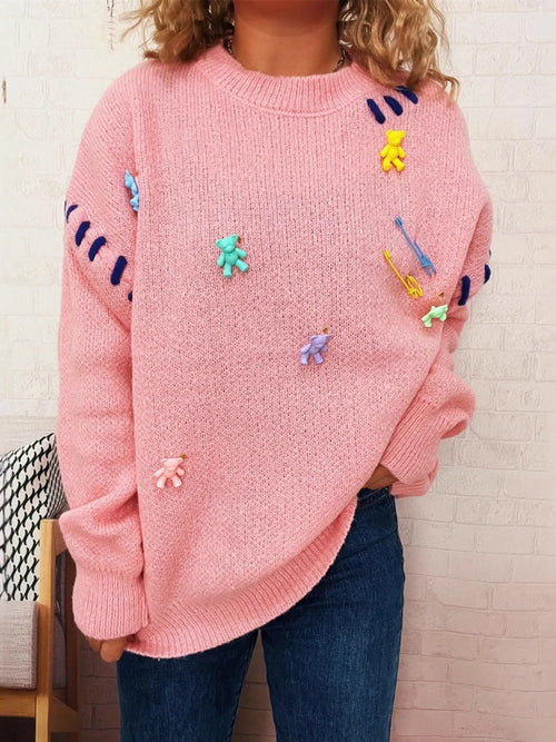 Pink round-neck knit sweater with colorful animal/applique graphics, side front view