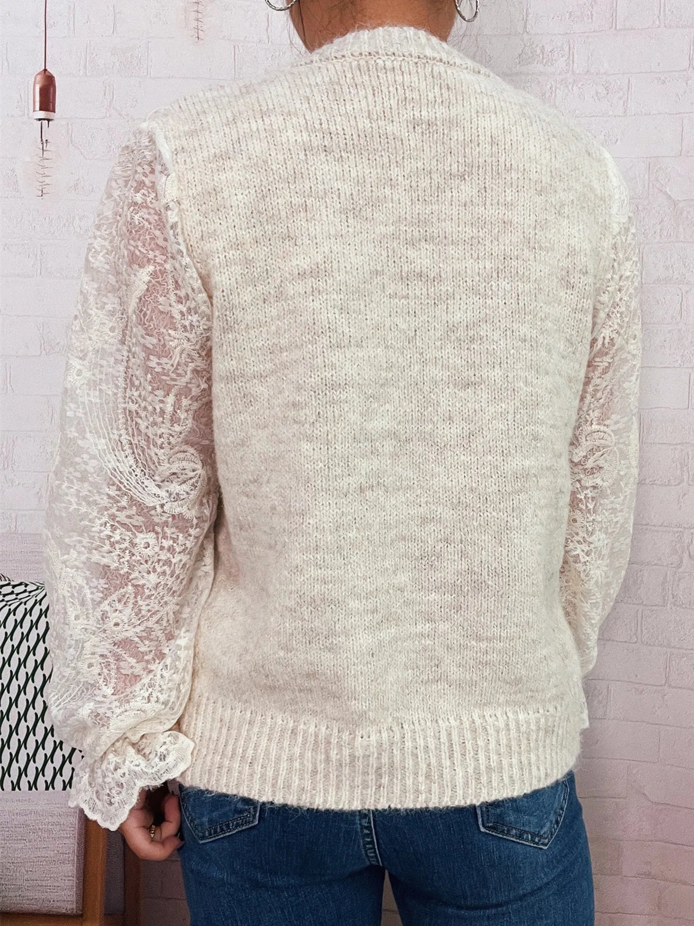 Back view of cream lace-sleeve button-up cardigan knit with lace trim at cuffs