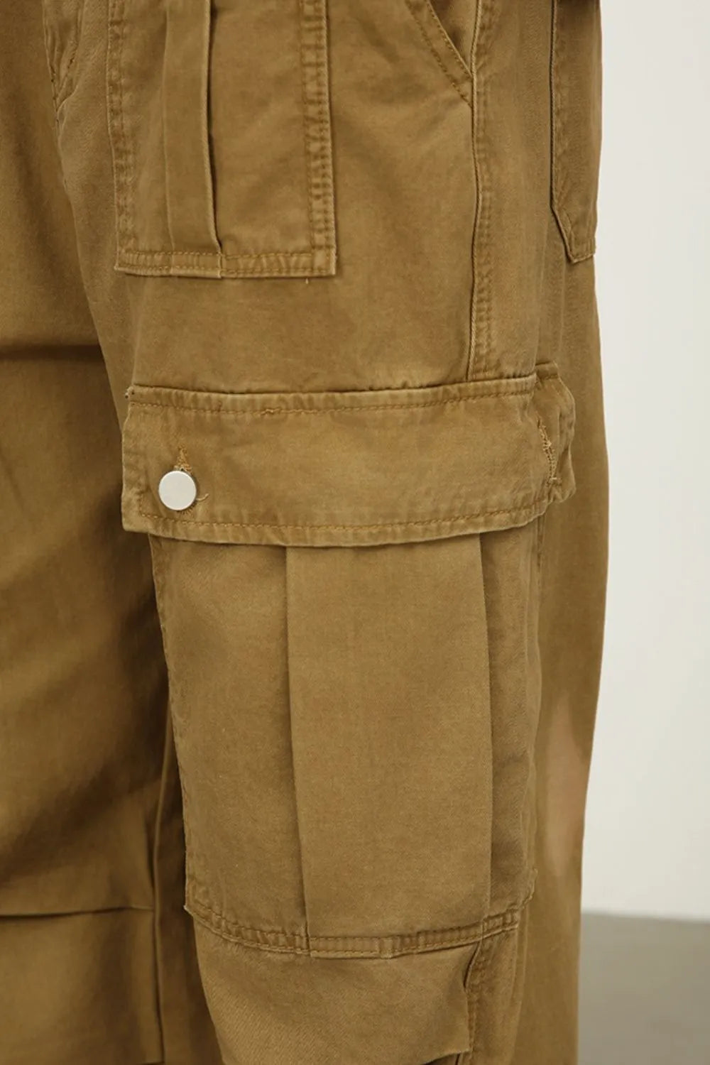 Khaki cargo jeans close-up of front flap pocket and button