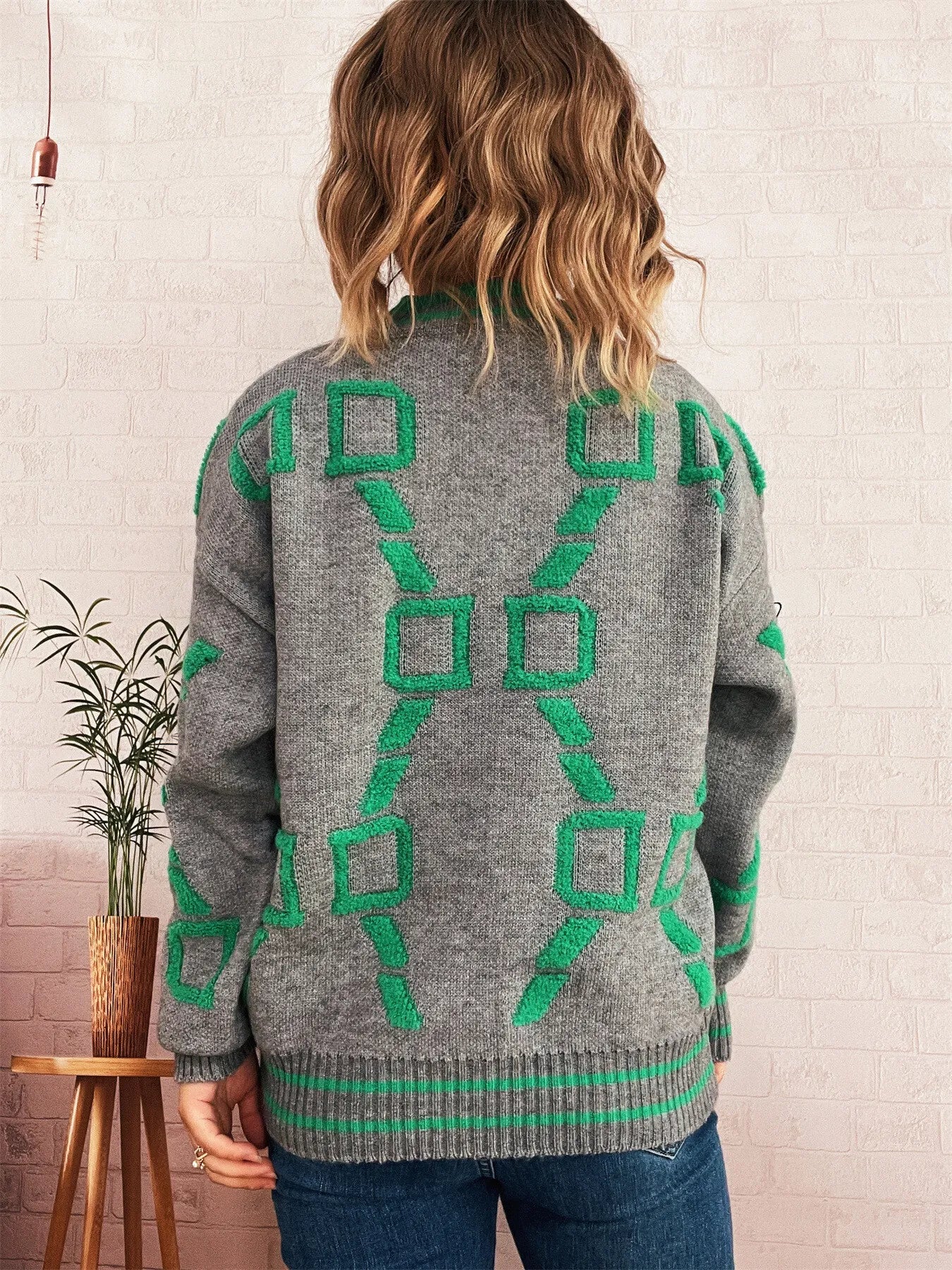 Grey long sleeve sweater with green geometric pattern on back and ribbed hem