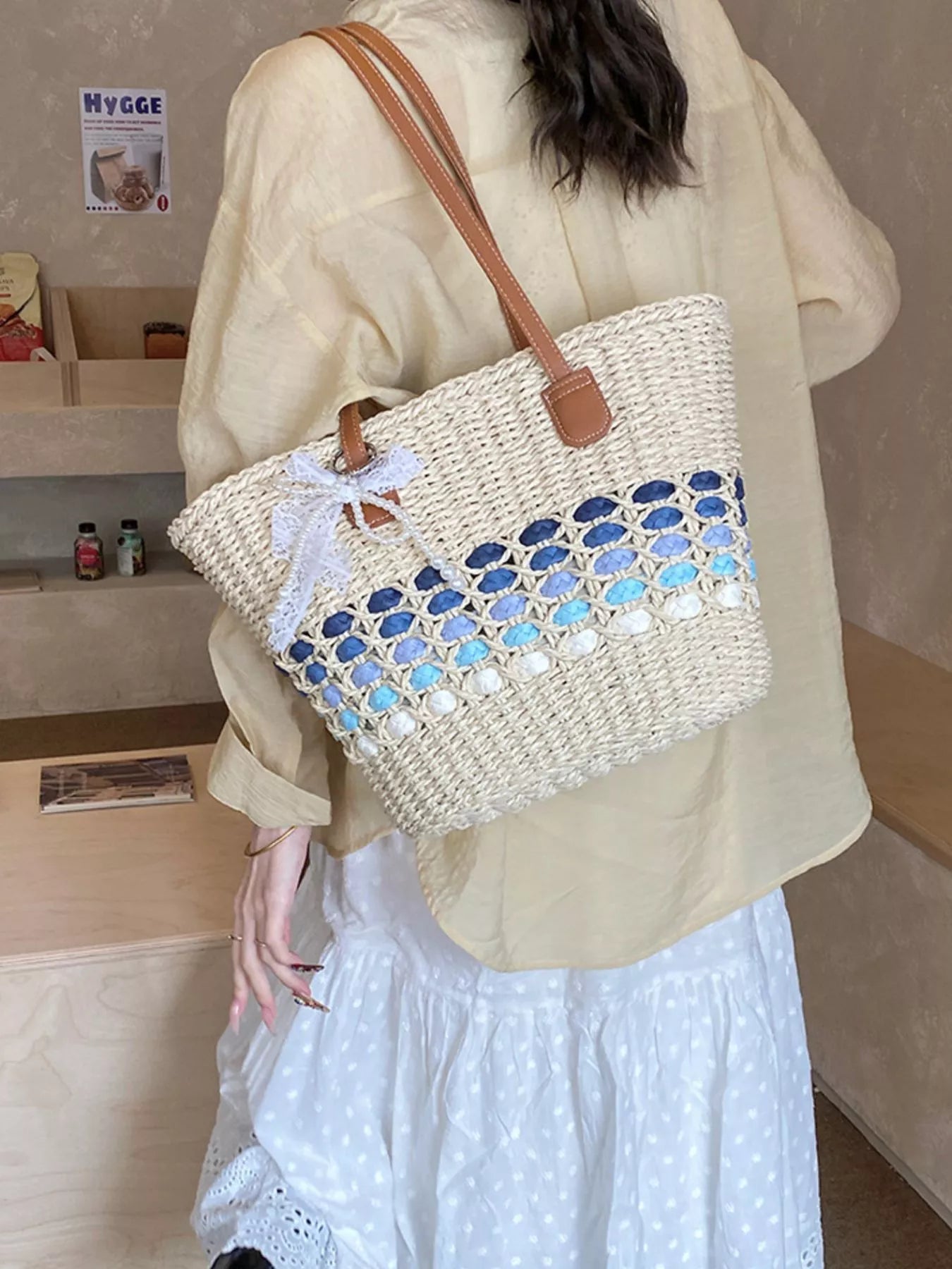 Woven straw shoulder bag with blue lattice trim and light-blue center, brown leather handles