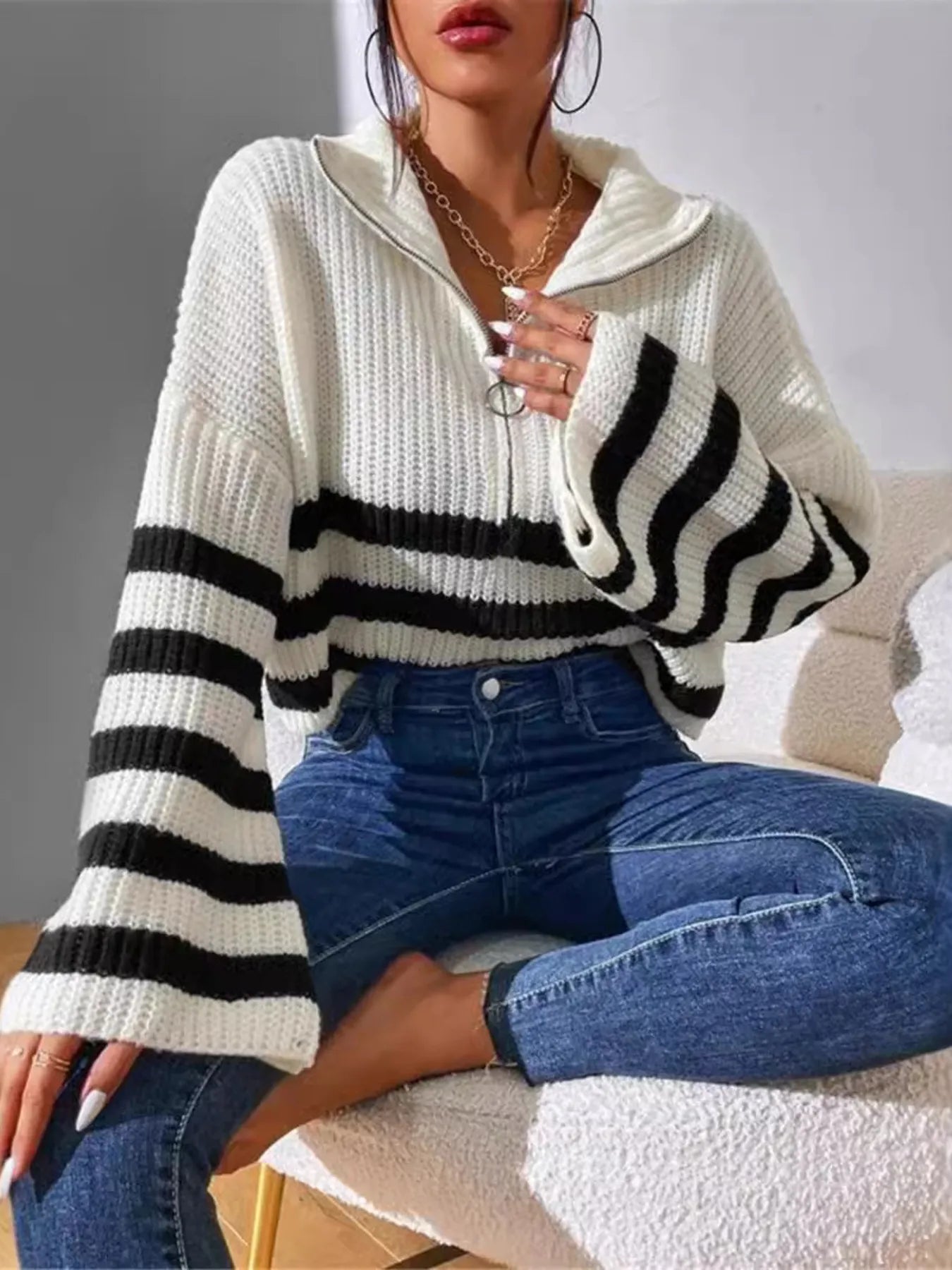 White ribbed half-zip cropped sweater with black-and-white striped bands across chest and arms