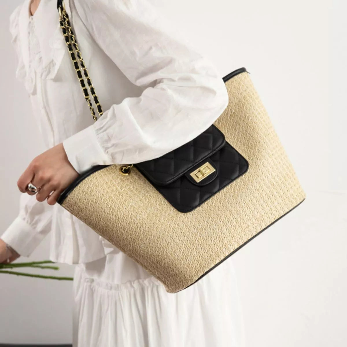 Woven straw tote with black quilted chain strap and gold-tone clasp