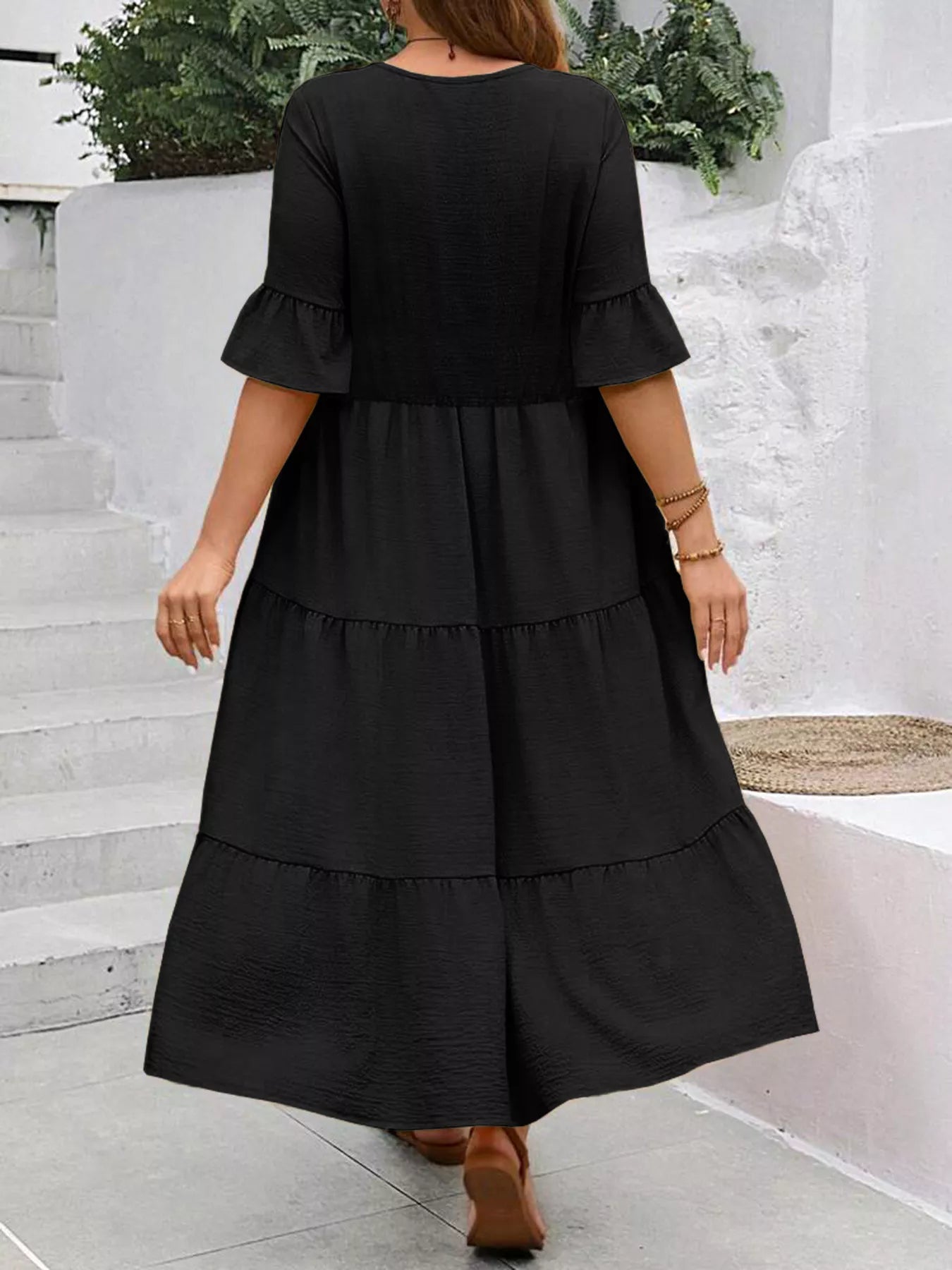 Black tiered midi dress with ruffle sleeves and layered back, elbow-length bell cuffs