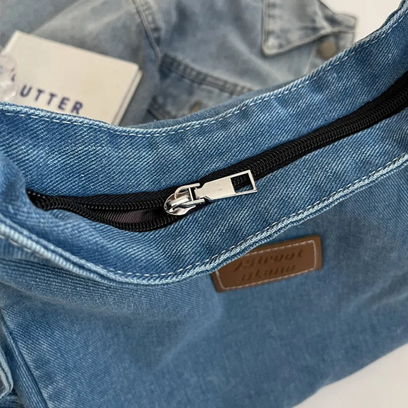 Denim shoulder bag interior pocket with black zipper and metal pull, brown logo patch