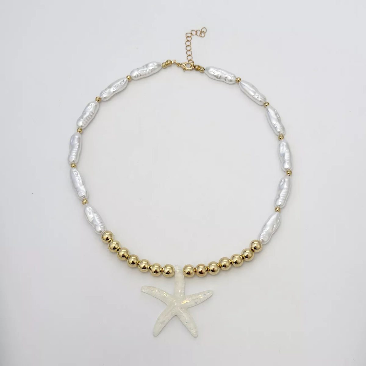 Starfish pendant necklace laid flat: white starfish over pearl-look and gold beads