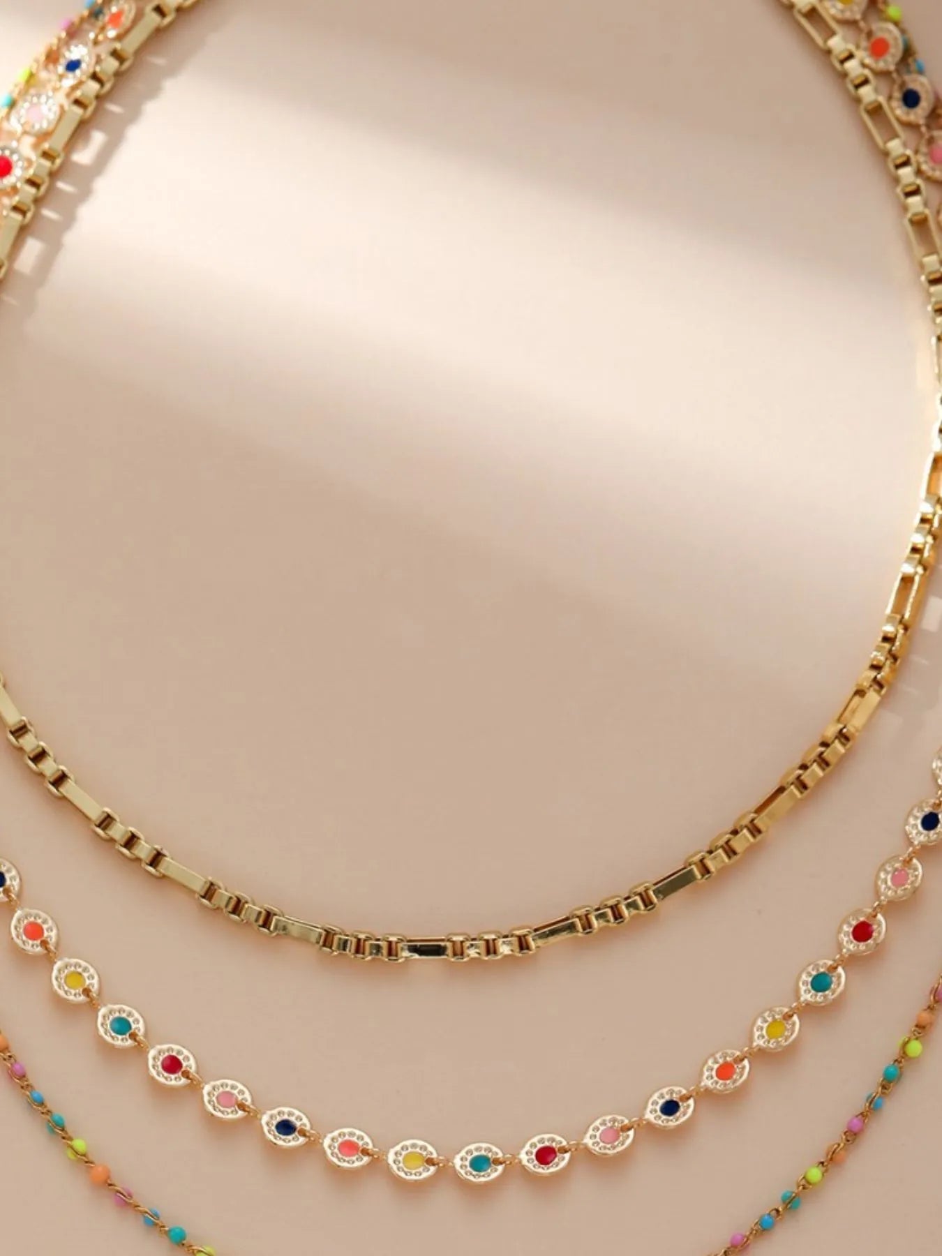 Gold-plated layered bead necklace with oval resin beads along a textured gold chain