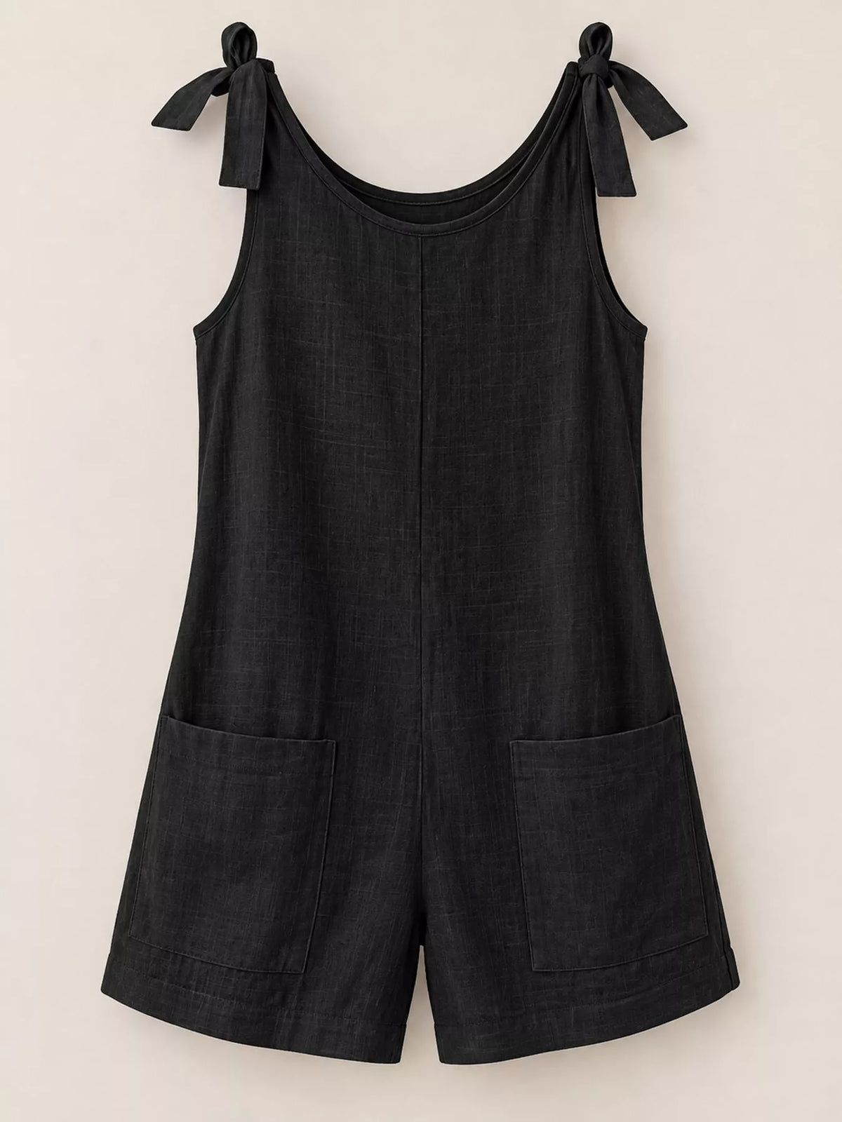 Black denim-style tie-shoulder bow romper with two front pockets.