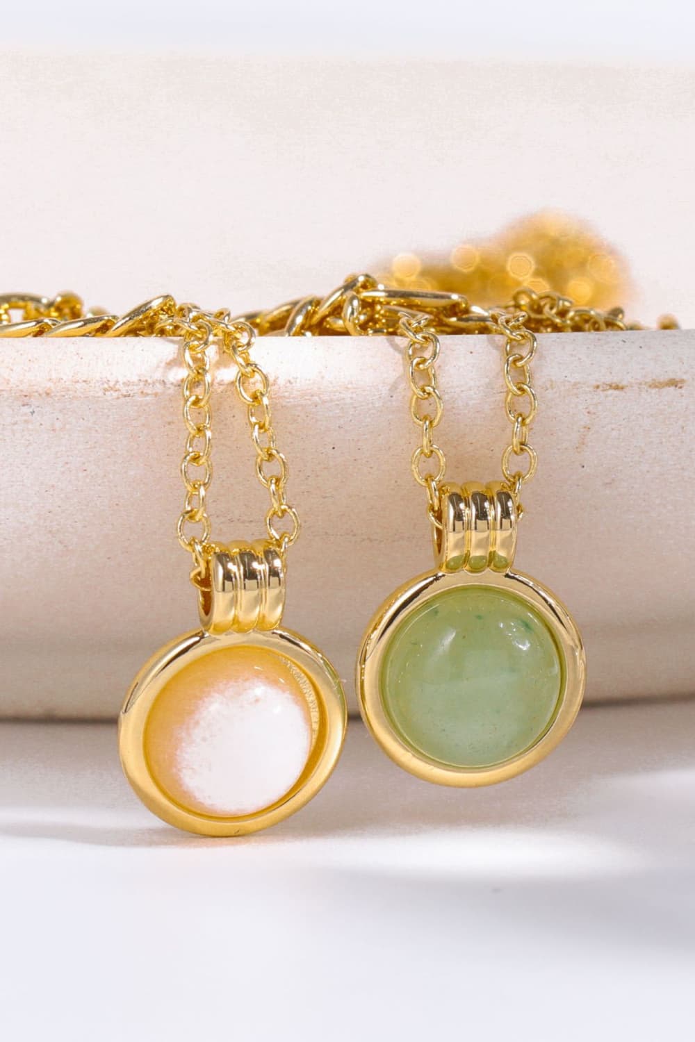 Gold-plated round pendant charms, one white and one green, on multiple chains