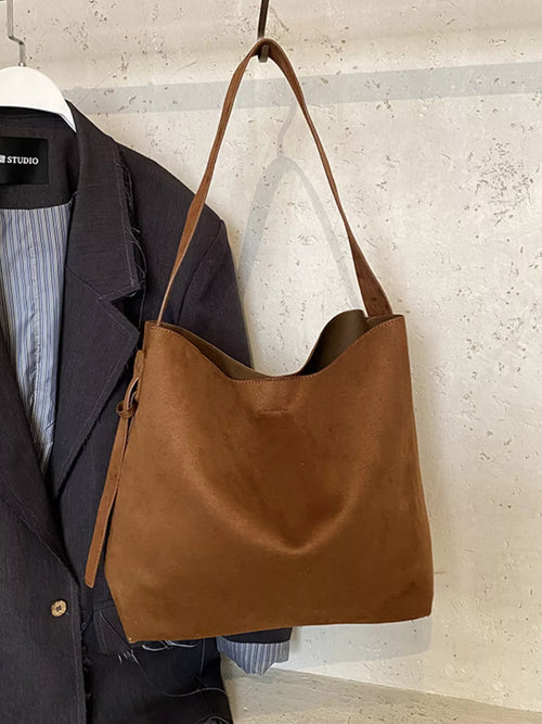 Brown tote bag with long adjustable strap and open top, suede-like finish