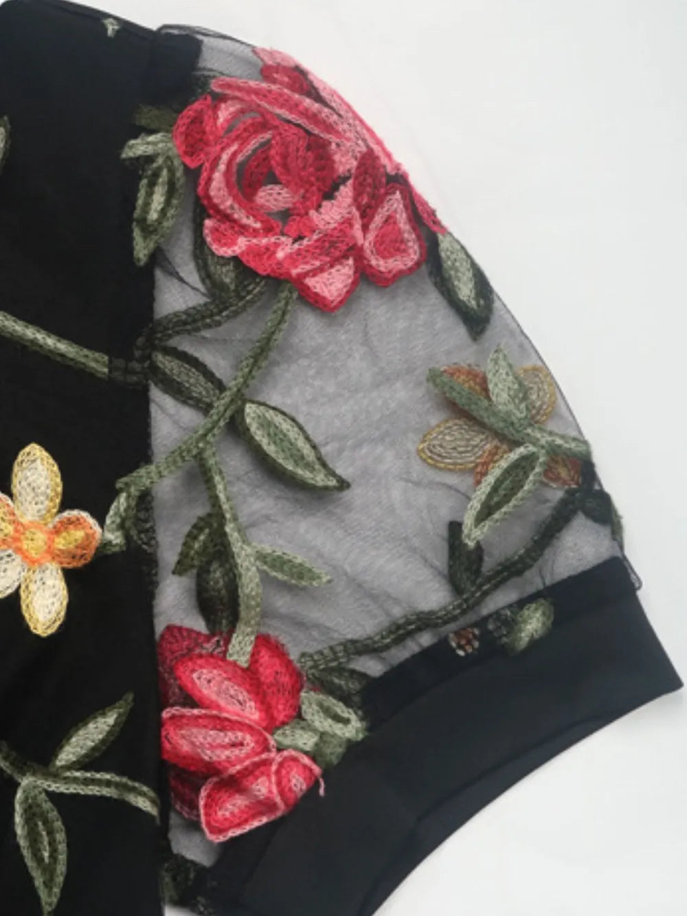 Black sheer sleeve panel with embroidered flowers and leaves on bodysuit