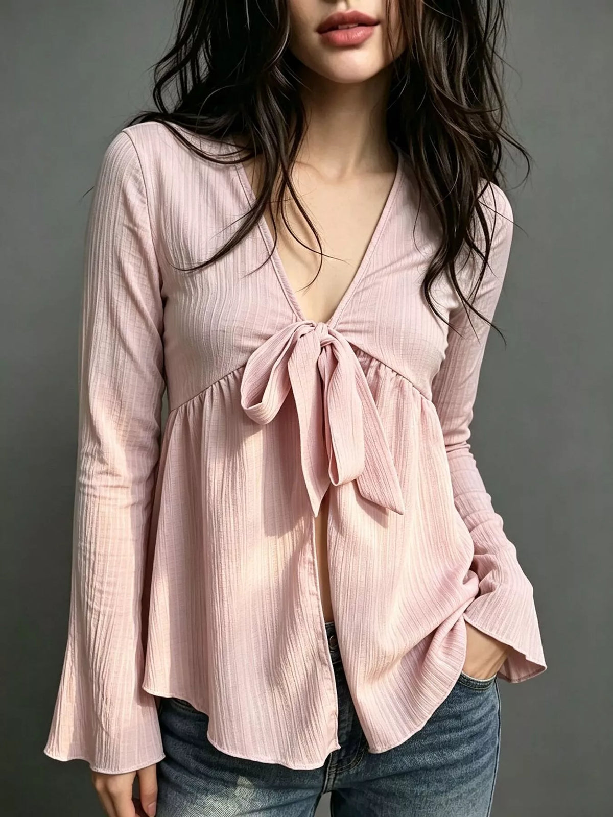Pink tie-front babydoll blouse with long flared sleeves and bow at the bust