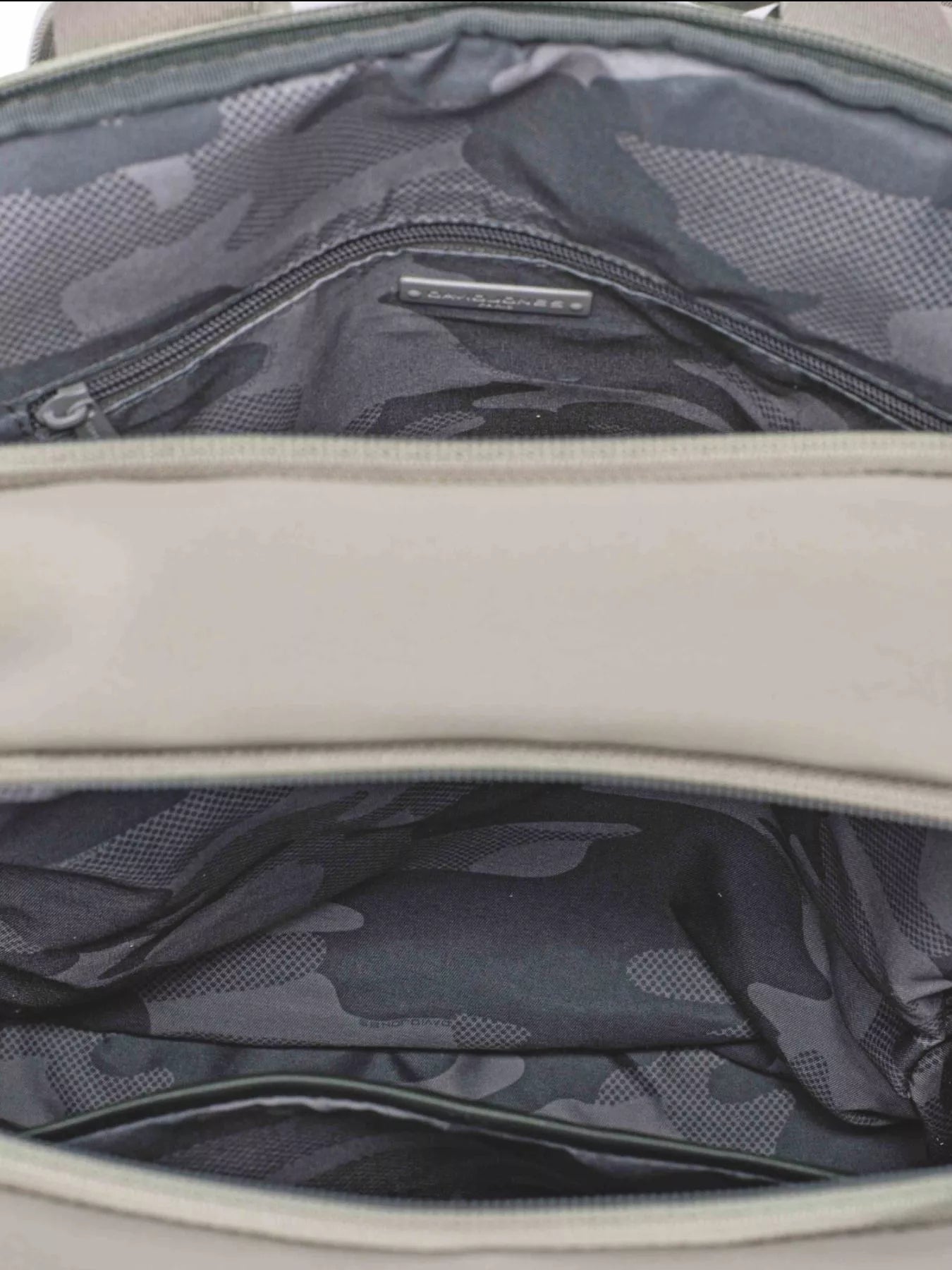 Backpack interior with zip pocket and dark camouflage-pattern lining