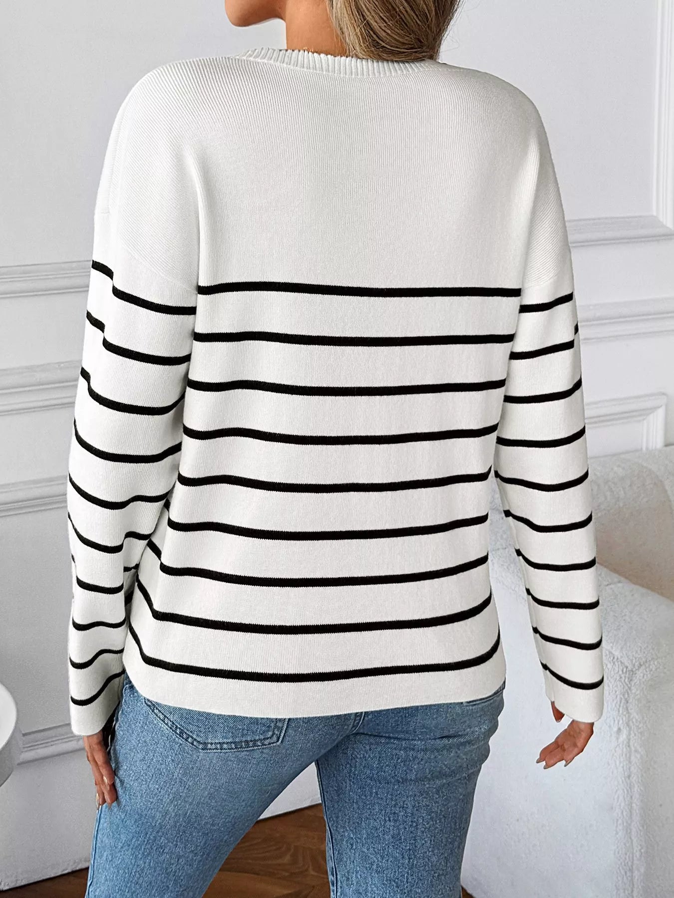 White back of V-neck long sleeve sweater with black stripe bands across shoulders