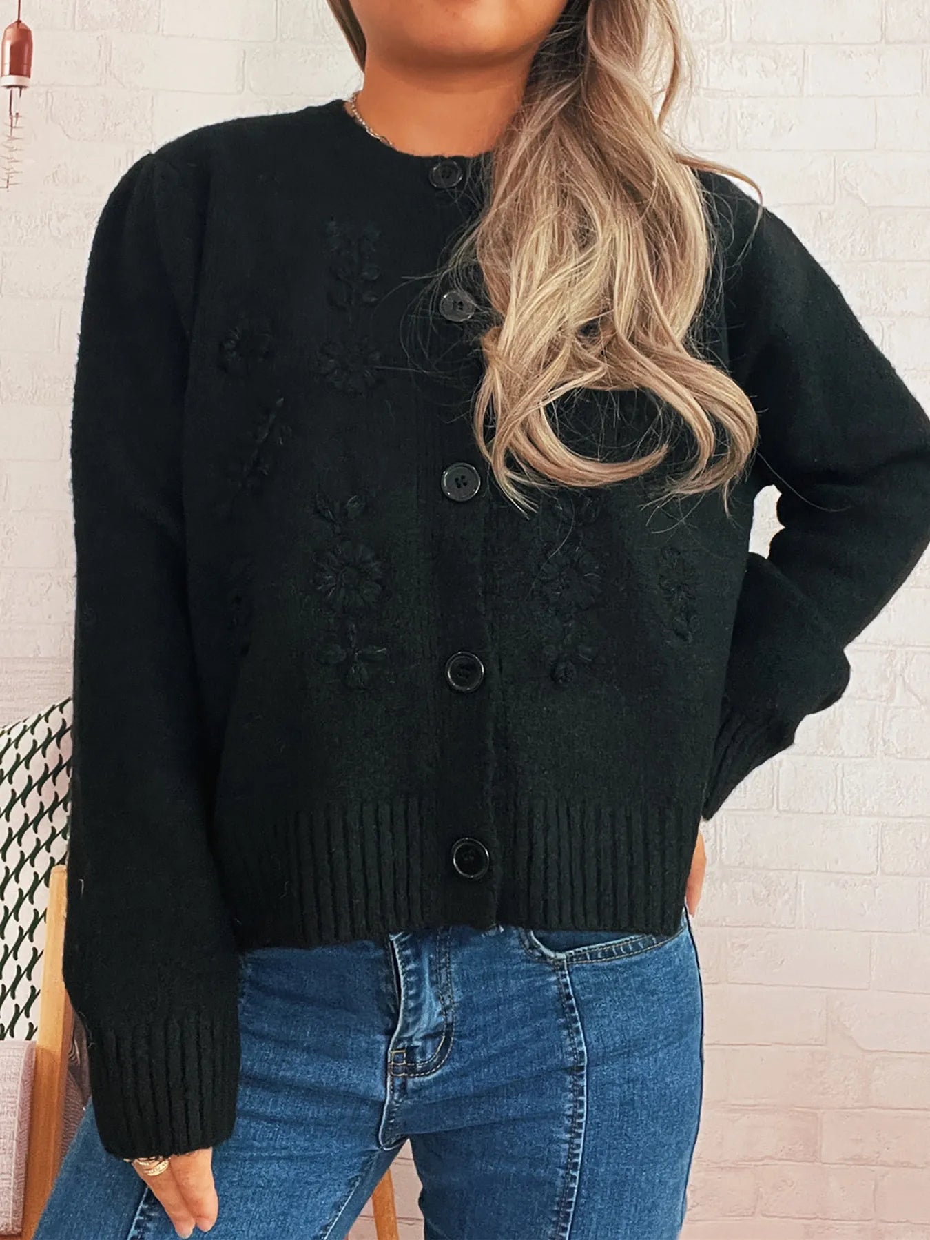 Black button-up cardigan with flower embroidery details and ribbed bottom hem.