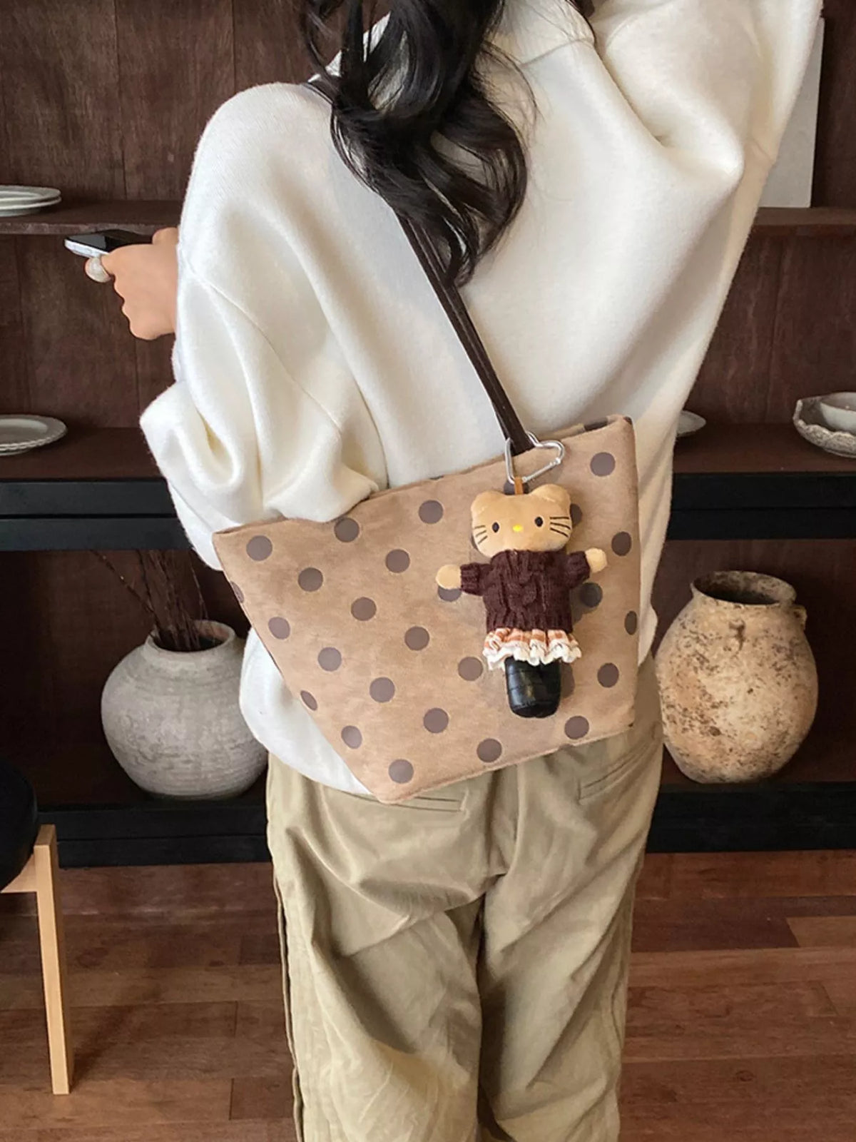 Tan suede shoulder handbag with dark polka dots and dangling cat charm