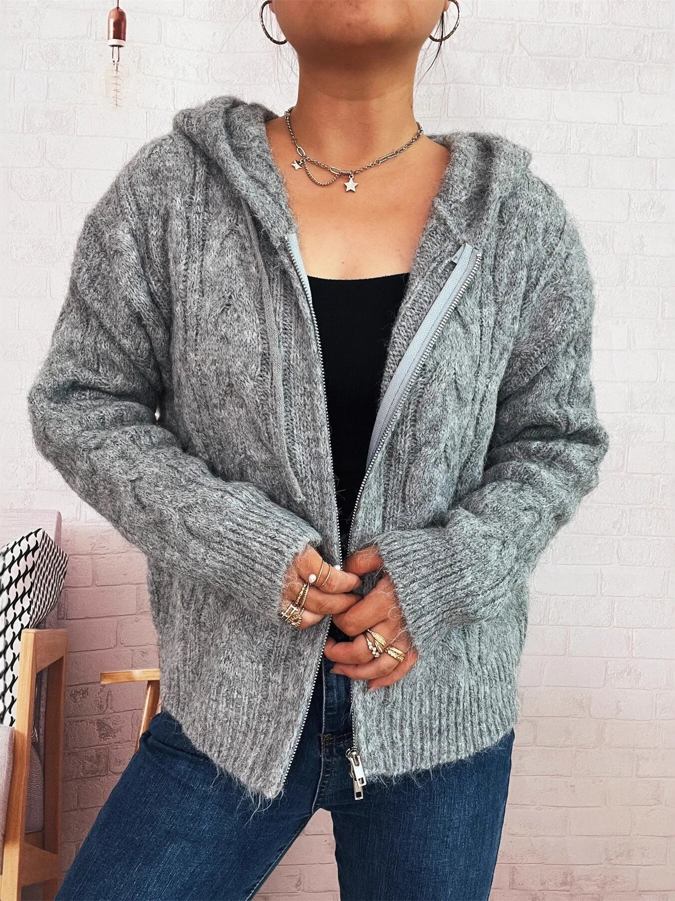 Gray cable knit hooded zip-up cardigan with long sleeves and ribbed hem and cuffs.