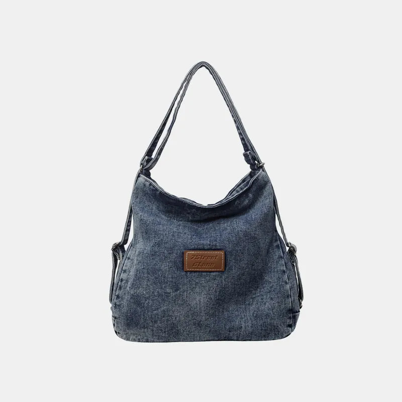 Dark denim shoulder bag with adjustable strap and brown front logo patch
