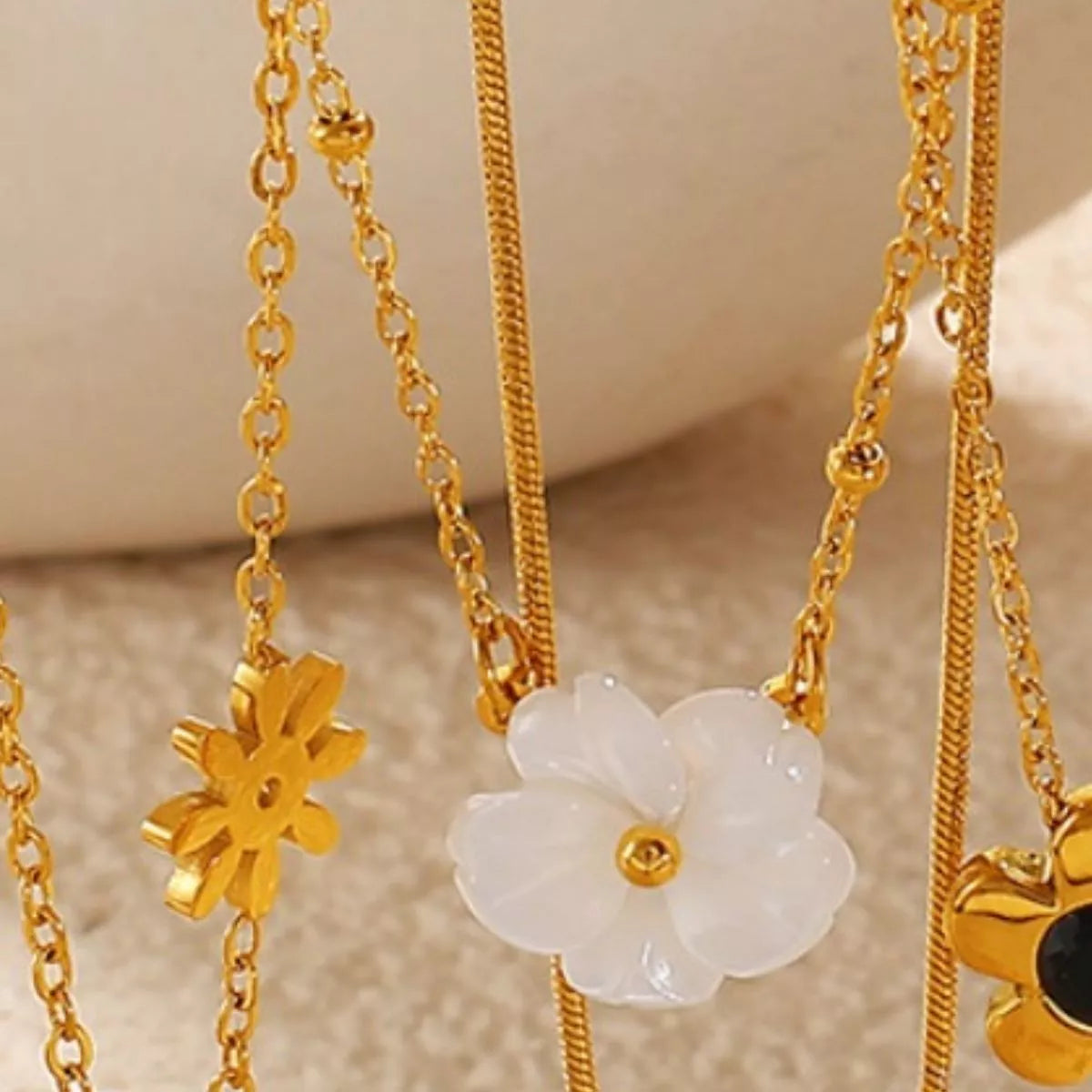 Gold-tone chain necklace with white flower pendant and small star-like charm