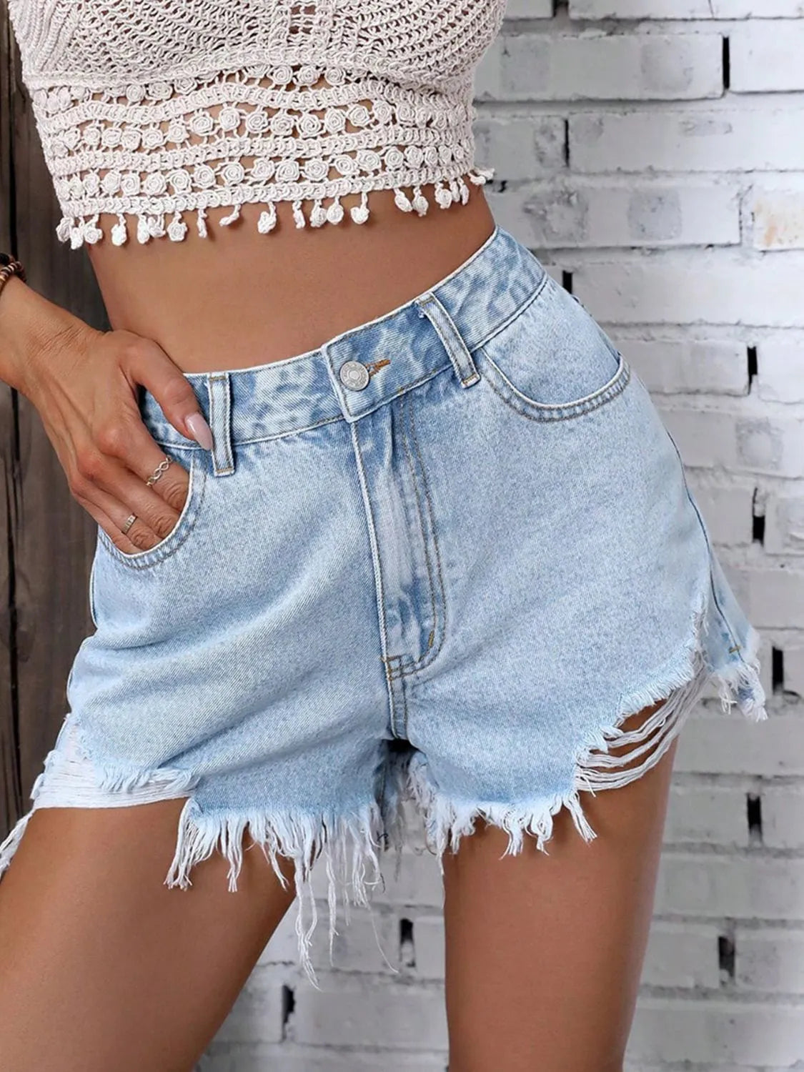 Light blue denim shorts with raw frayed hem, button closure, and stitched front seams
