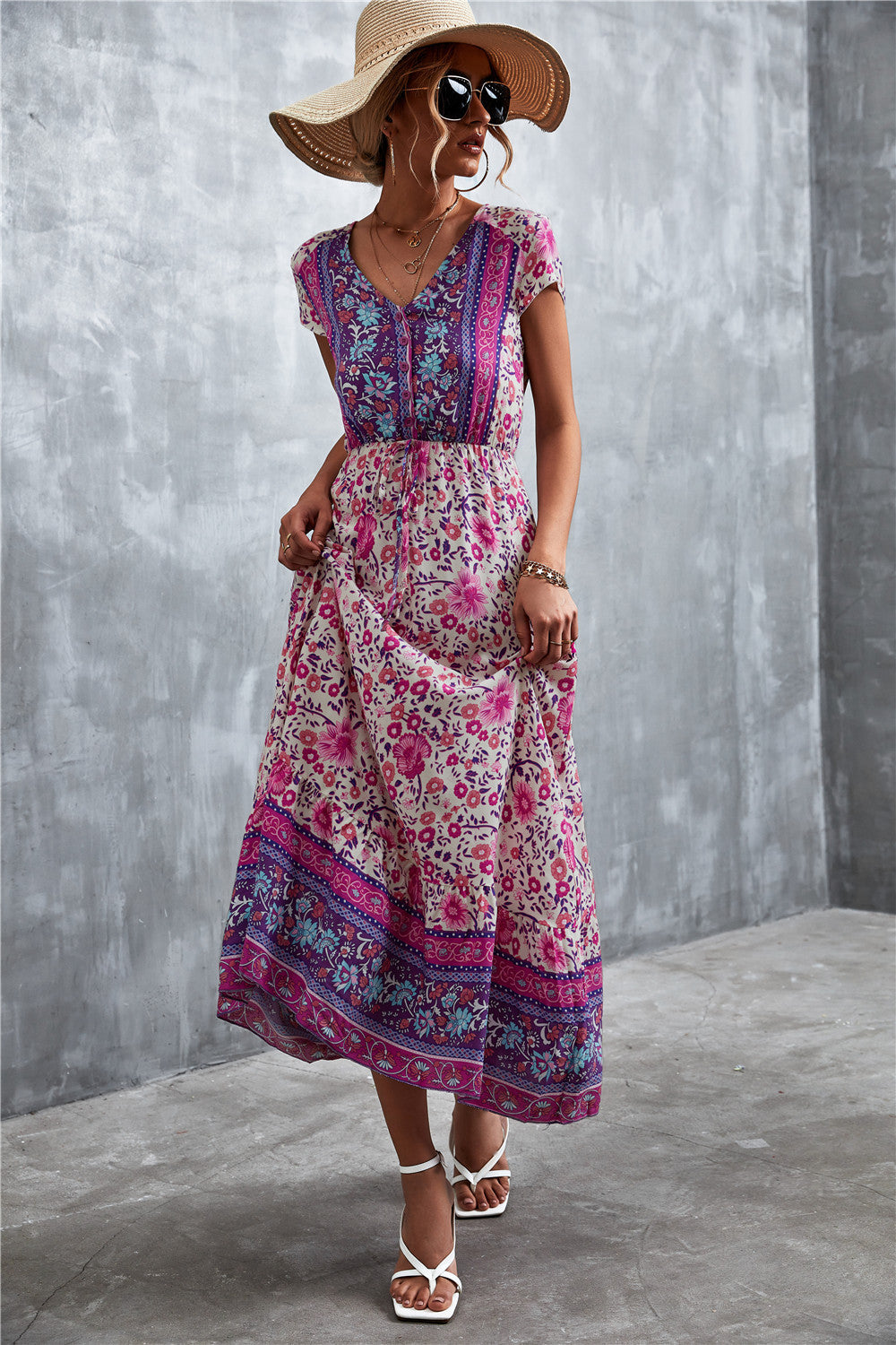 V-neck printed maxi dress with short sleeves, purple base, pink floral pattern and blue band.