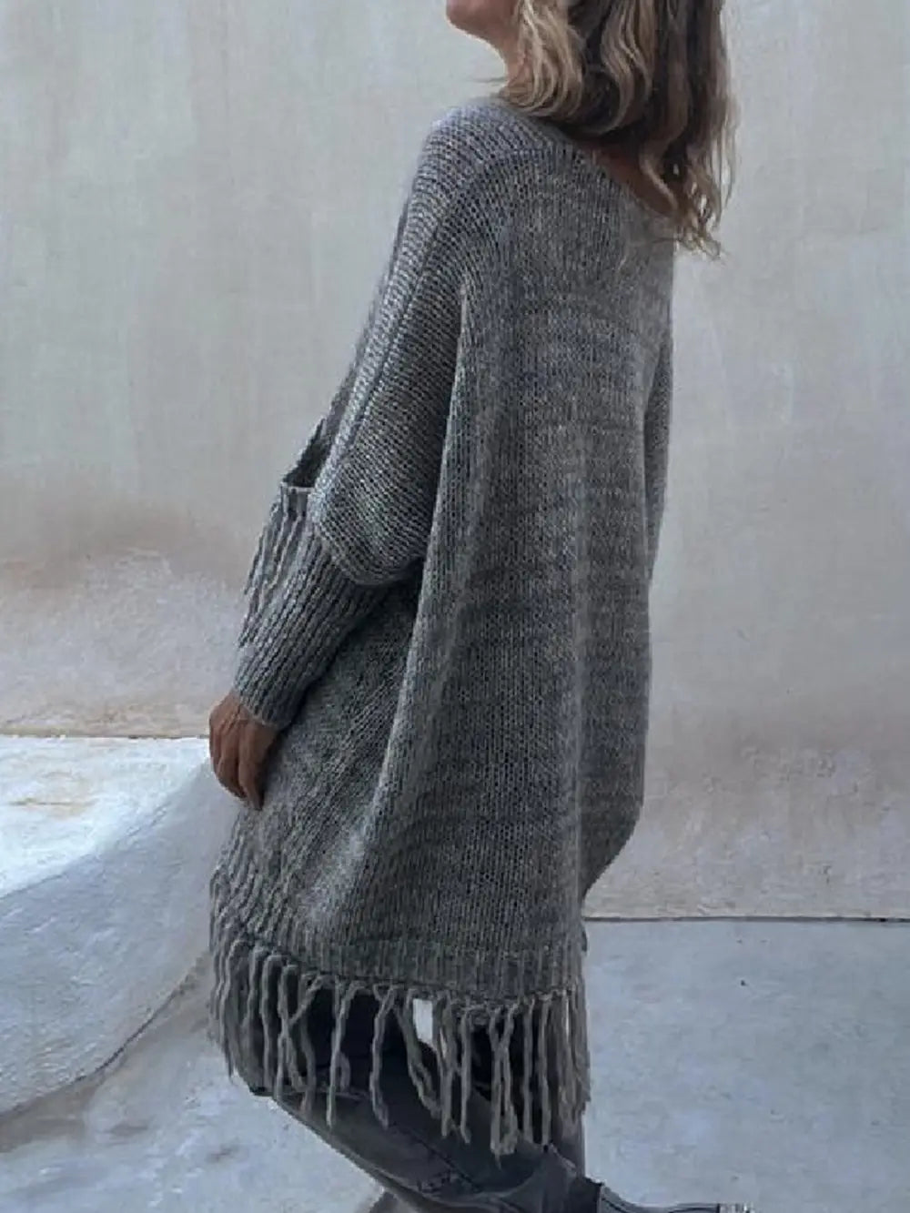 Dark gray long-sleeve sweater side view with fringe trim at cuffs and hem.