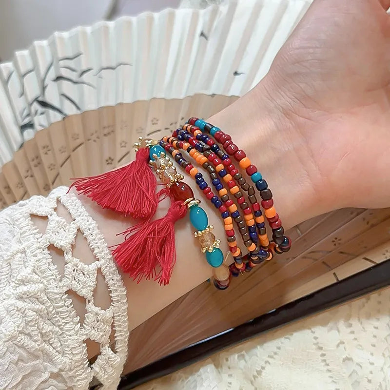 Stacked beaded tassel bracelet in red and blue with gold charms and red tassels