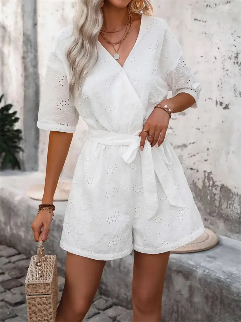 White eyelet romper with puff sleeves, V-neck, and bow-tied waist