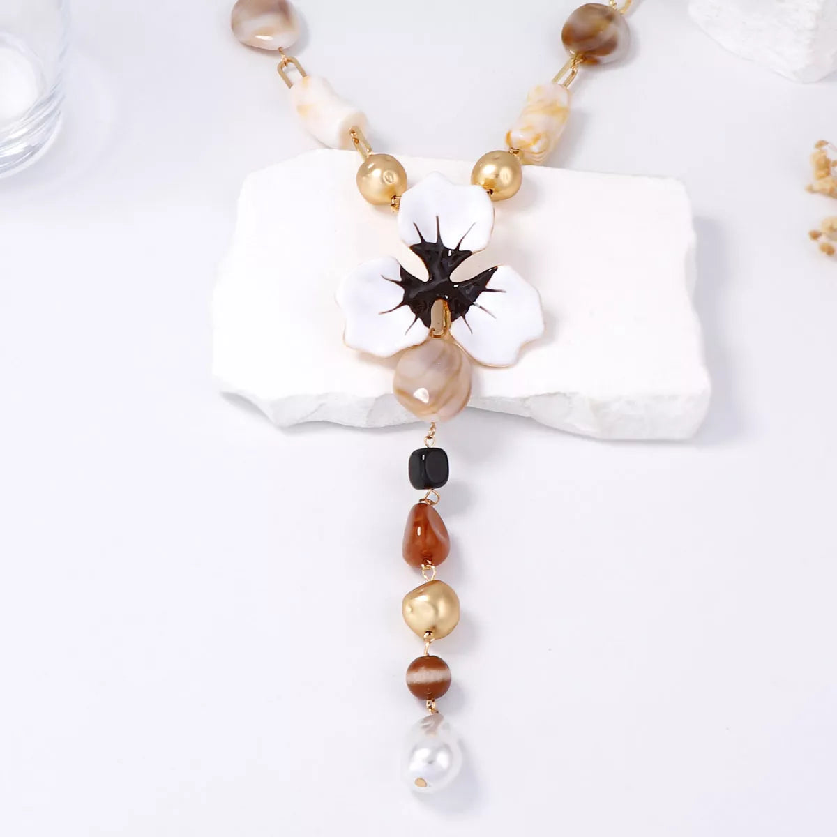 Y-shaped flower pendant necklace with white petals, black center, and mixed bead strands