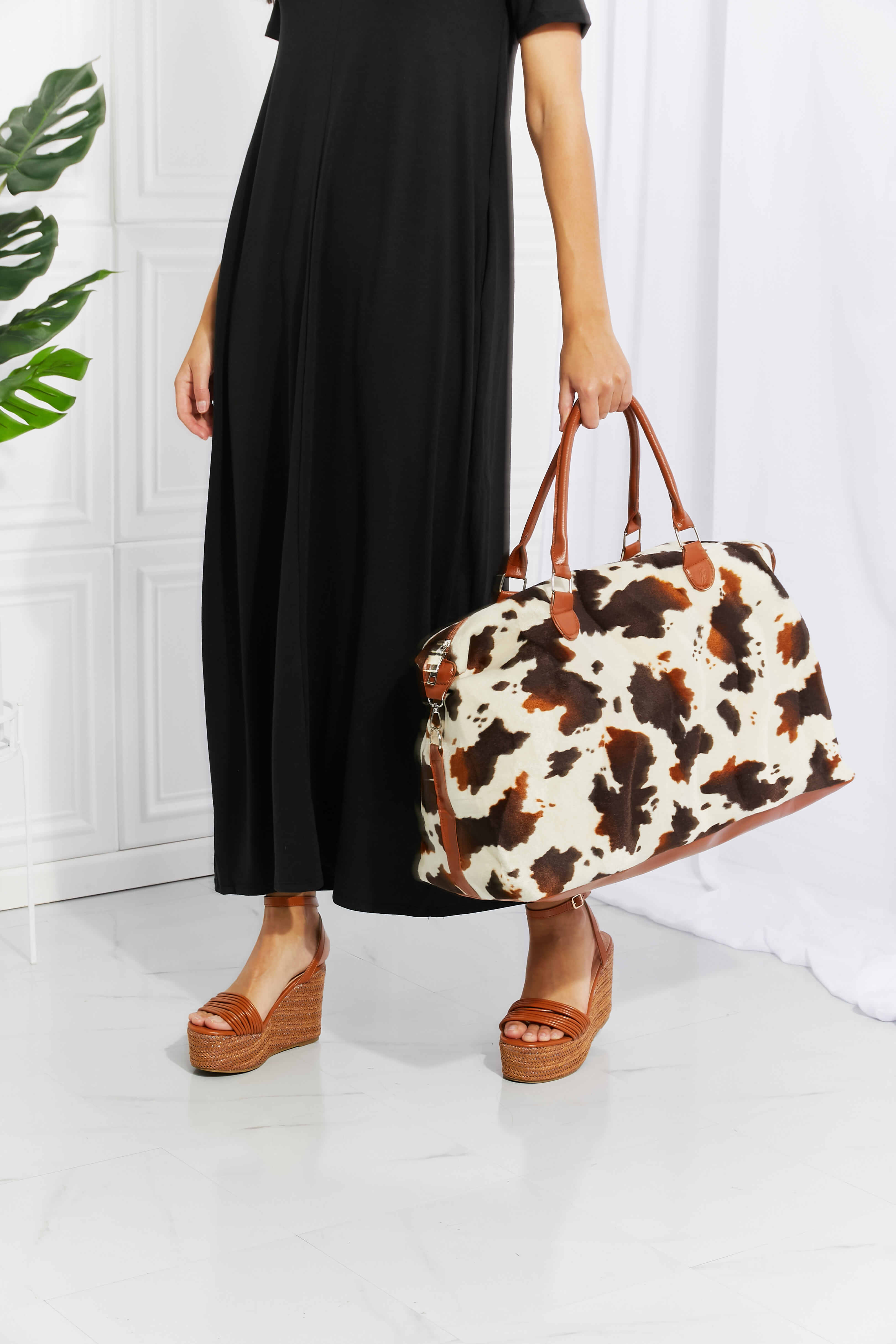 Animal print plush weekender bag with brown top handles and bold cow-spotted print