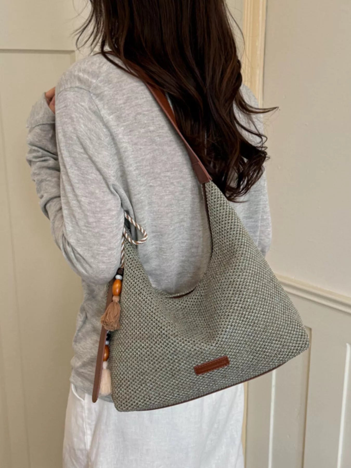 Medium woven shoulder bag side view, tassel fringe and textured gray weave with brown strap
