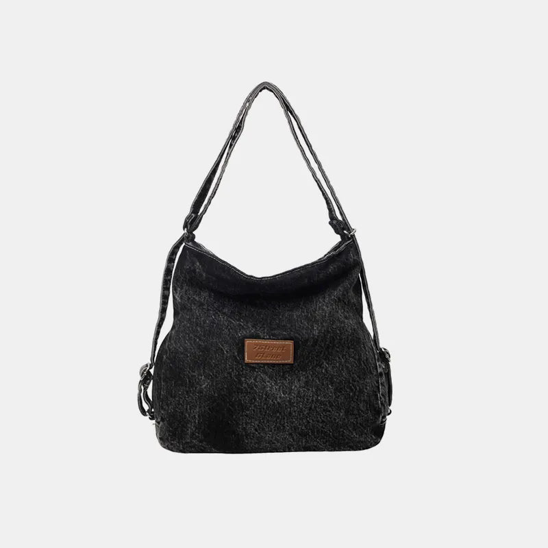 Dark denim shoulder bag with adjustable strap and rectangular leather logo patch