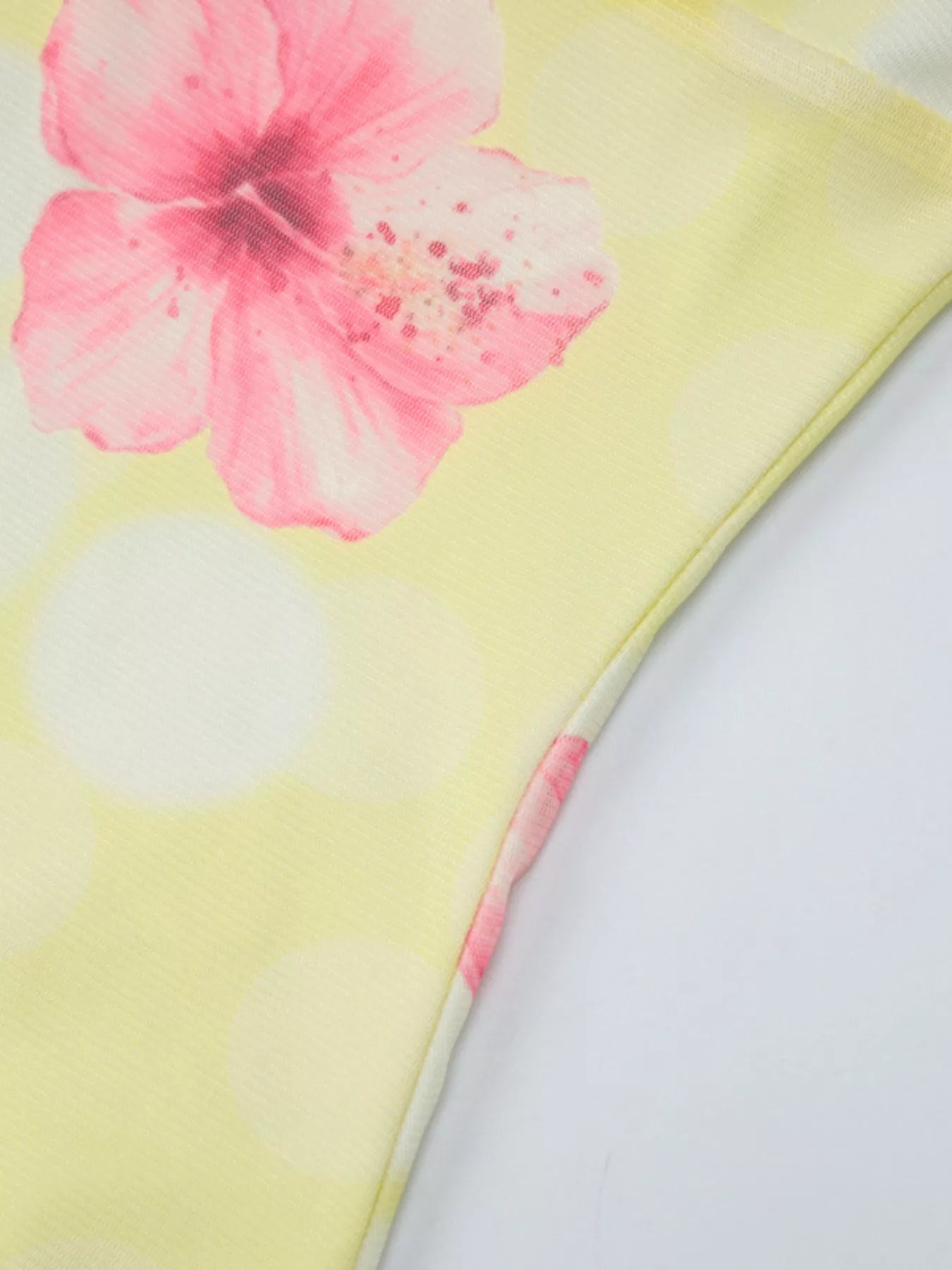 Close-up of yellow sheer fabric with pink floral print and diagonal fold